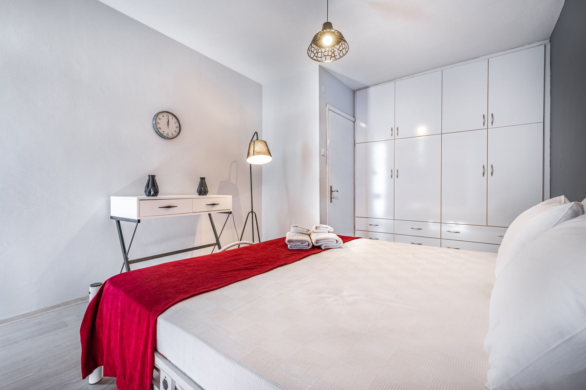 Cozy hotel room featuring a white bed, red throw, and roll-in shower.