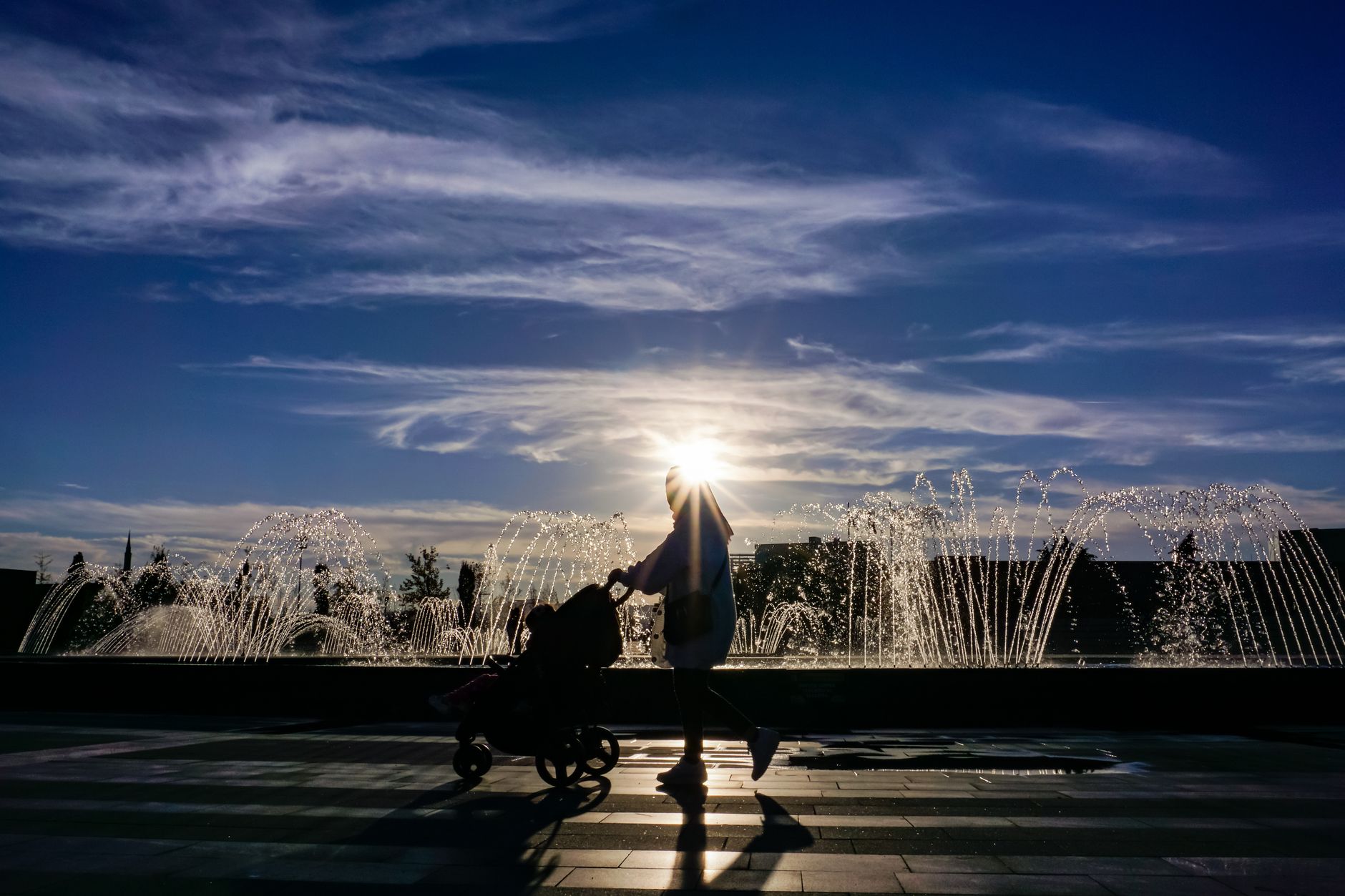 Silhouette of a family walking by a fountain in Istanbul at sunset.