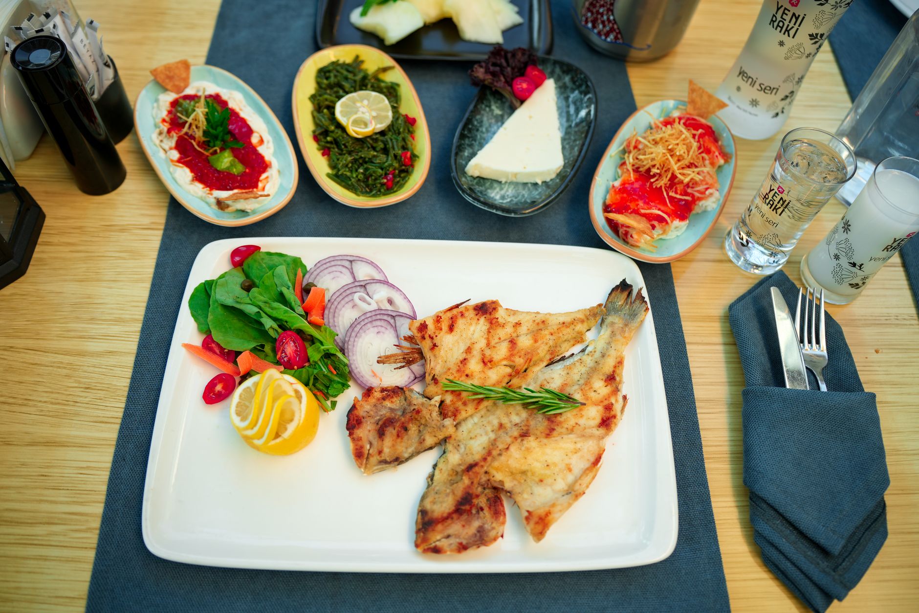 A vibrant seafood platter featuring grilled fish, fresh vegetables, and various Turkish mezes.