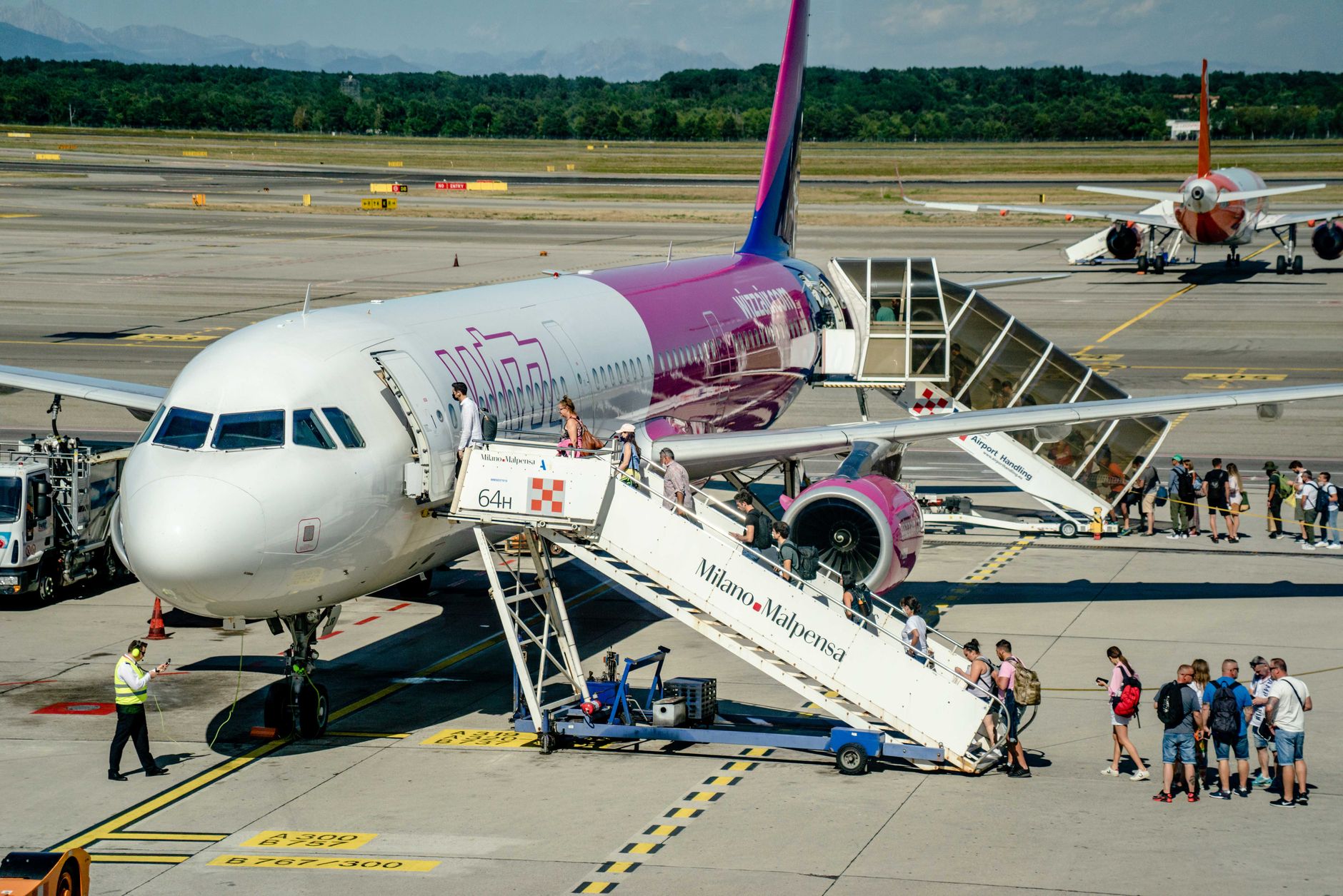 Travellers boarding an aircraft at Milano Malpensa for Türkiye, warm day at the airport.
