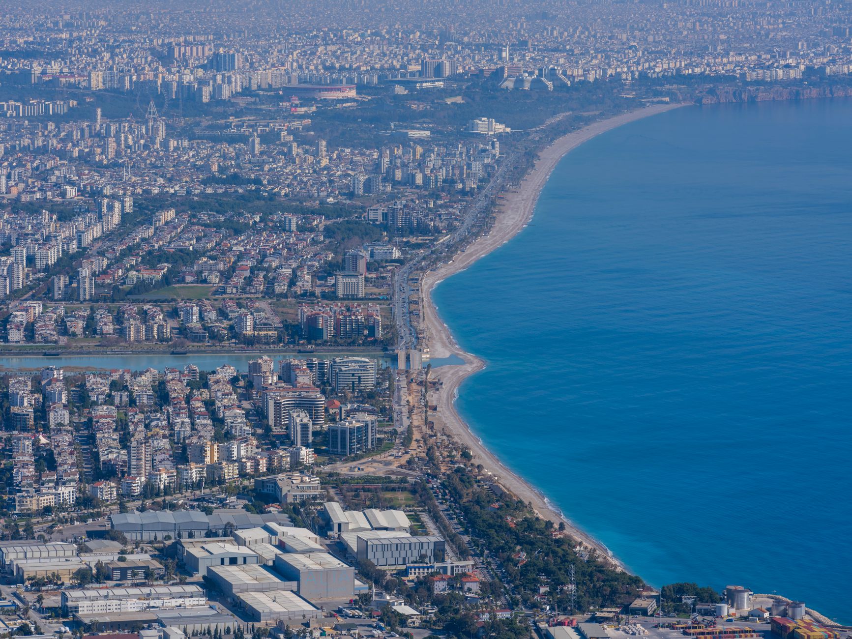 Aerial view of Antalya showing the coastline, urban areas, and blue waters.