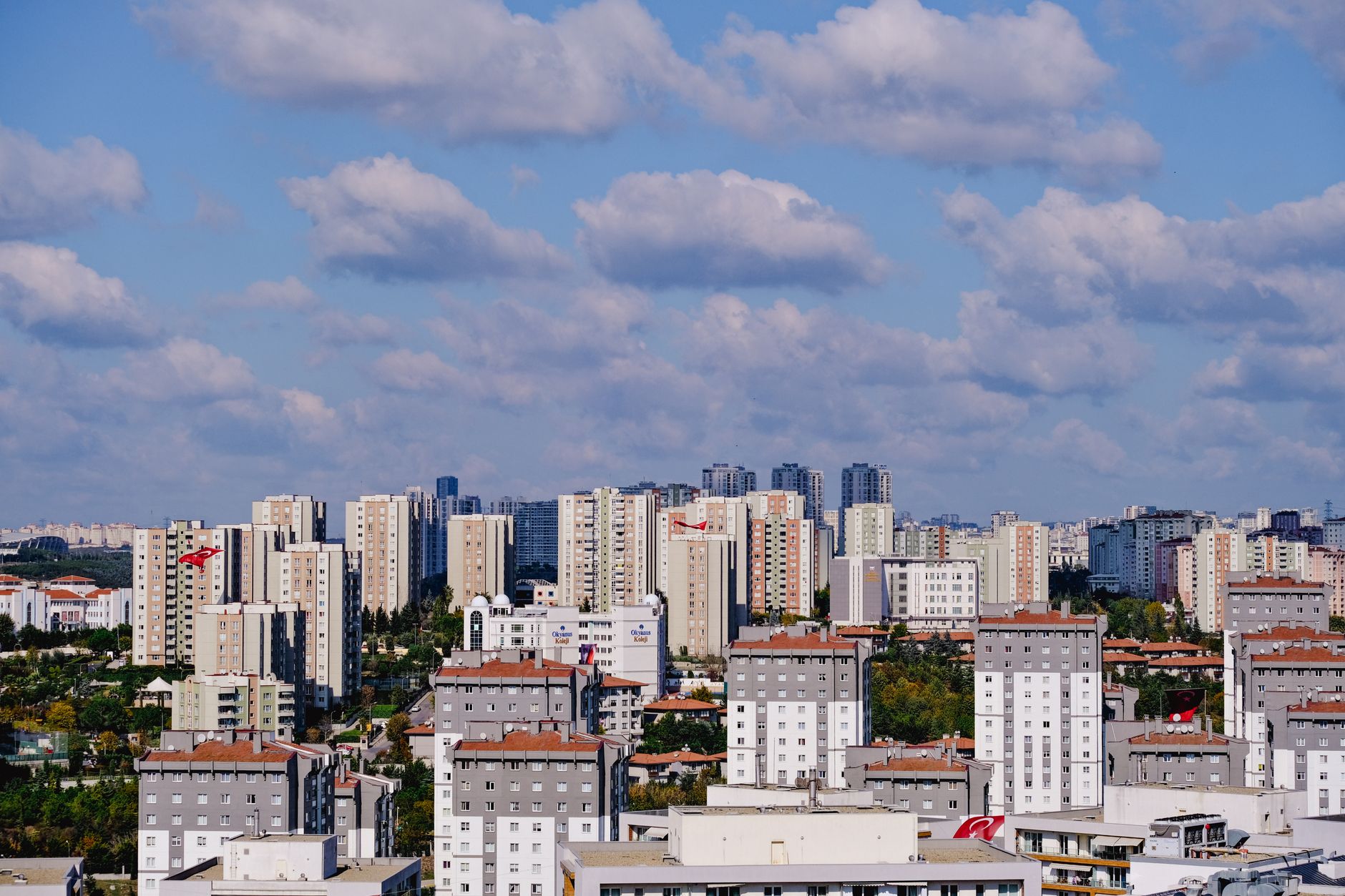 Bright view of modern apartment buildings and urban skyline in Turkey under a blue sky with clouds.
