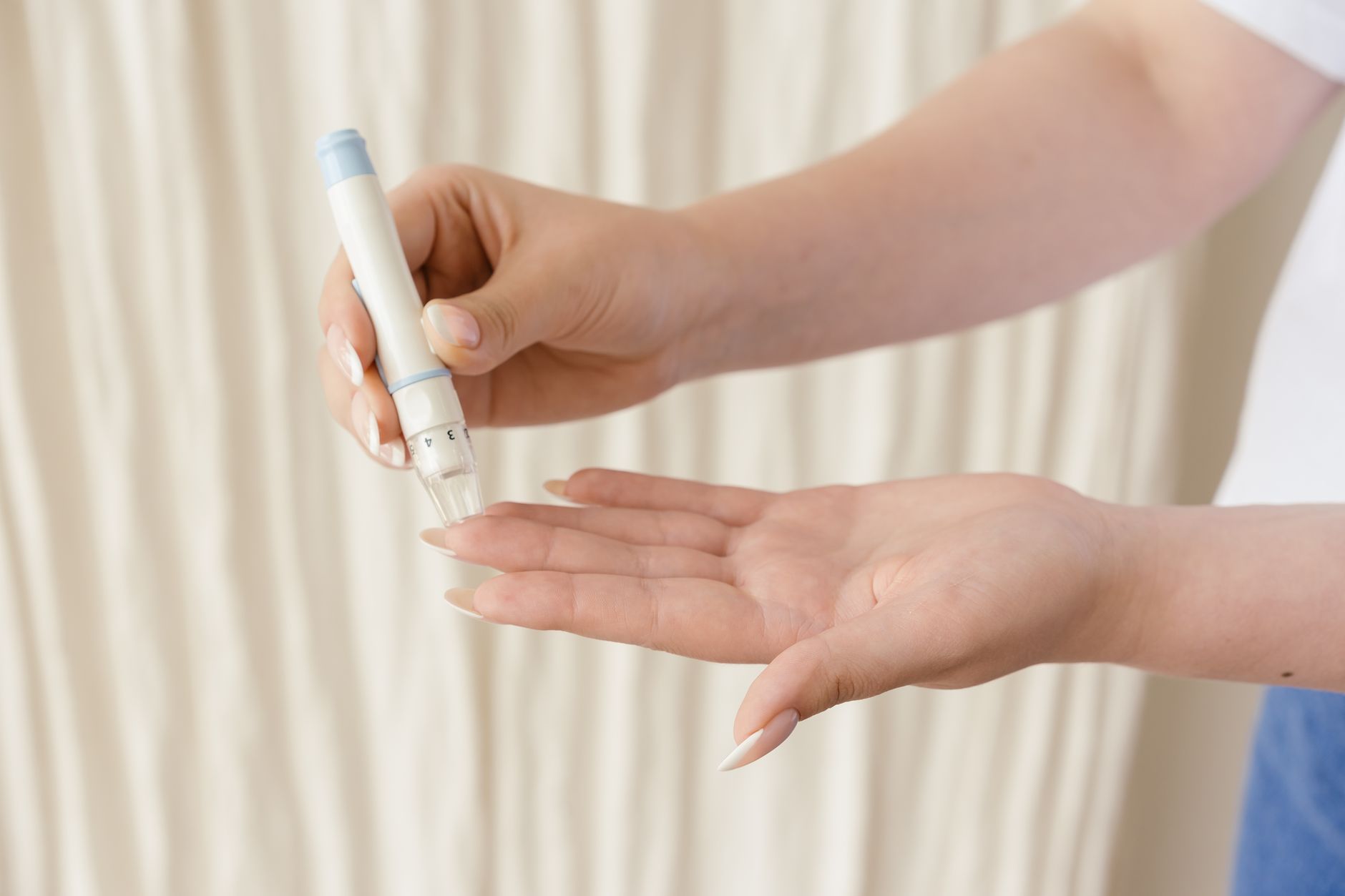 Close-up of a hand using a skin-prick testing device on another hand.