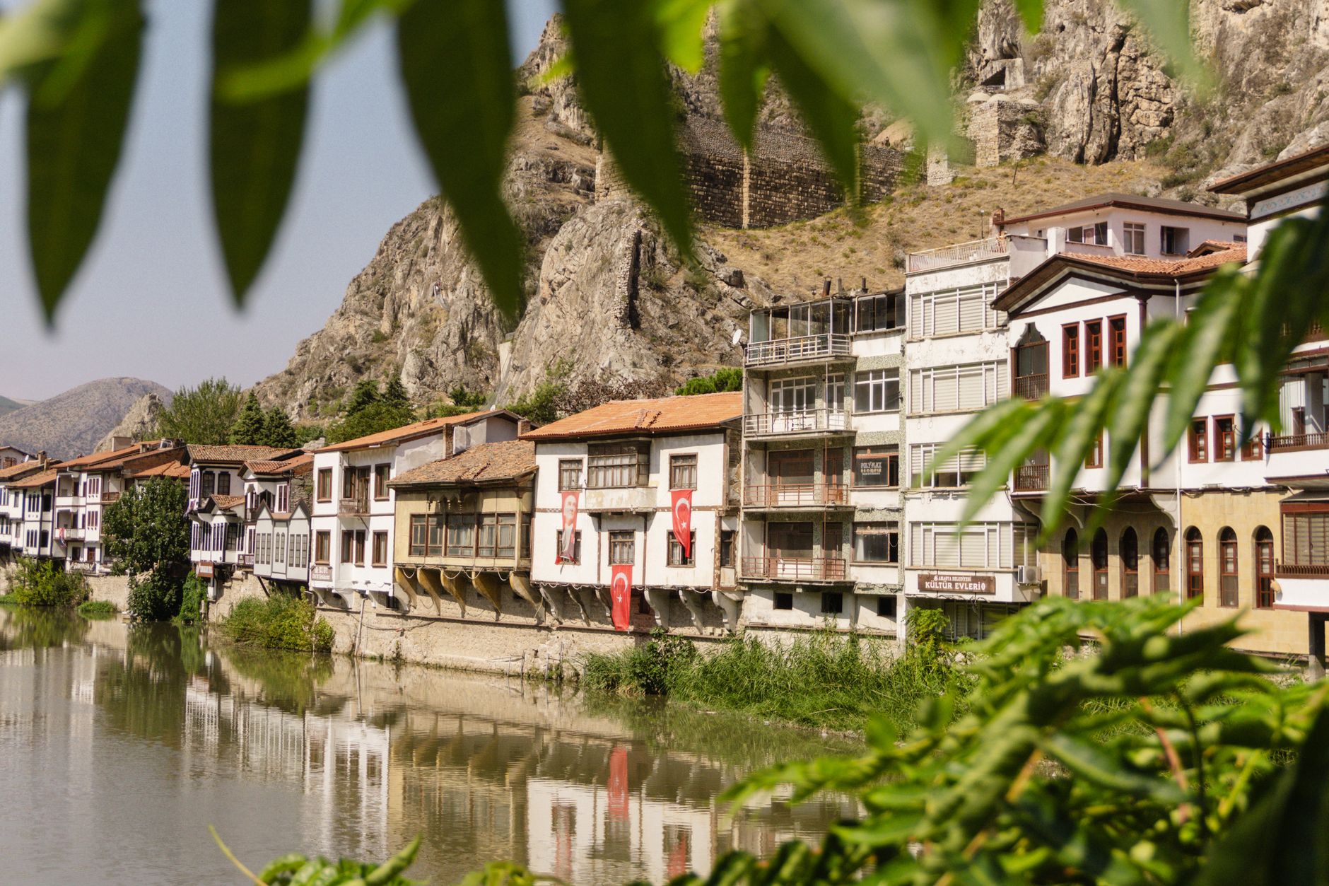 Scenic view of riverside homes with reflections, framed by greenery.