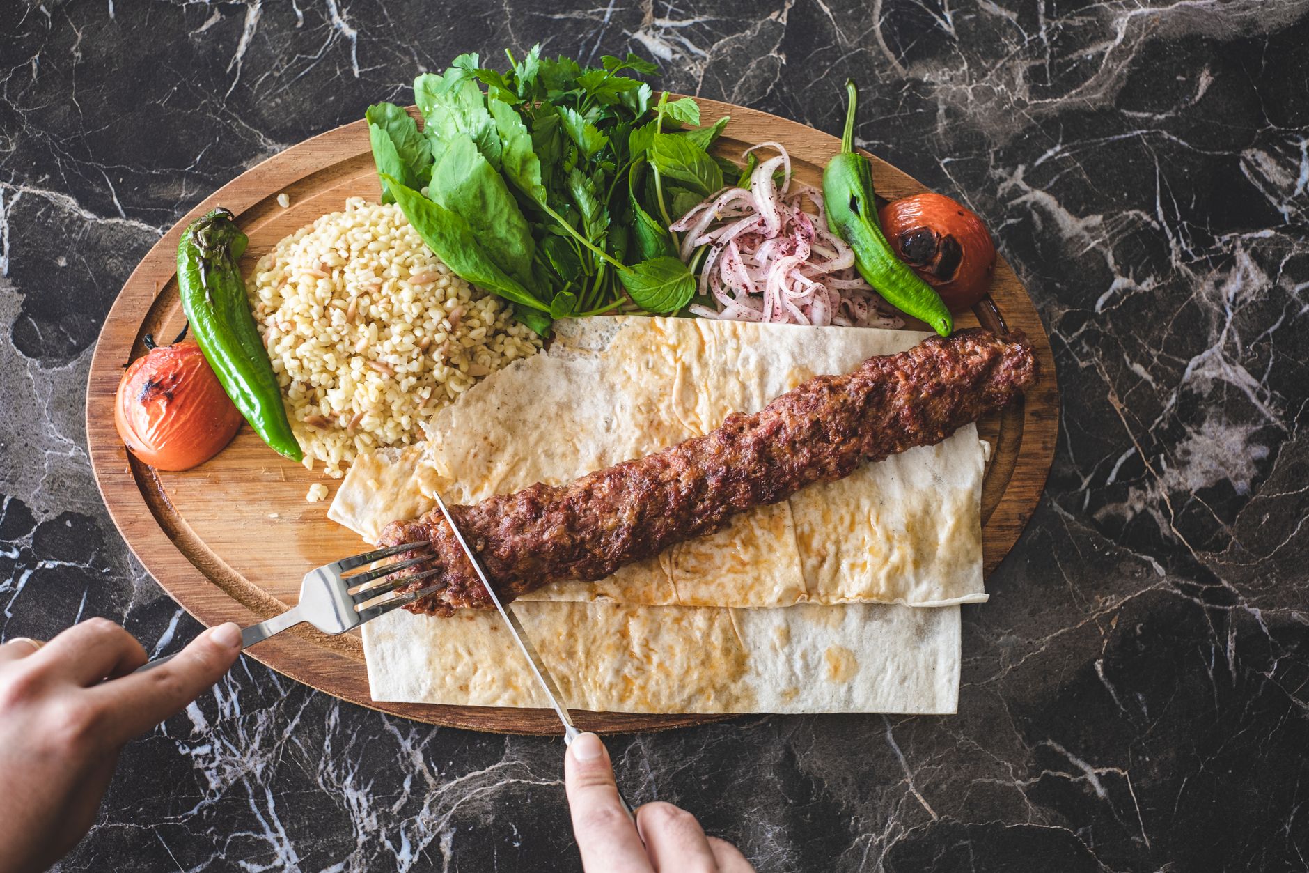 Тарелка с кебабами на гриле, рисом, овощами и зеленью.