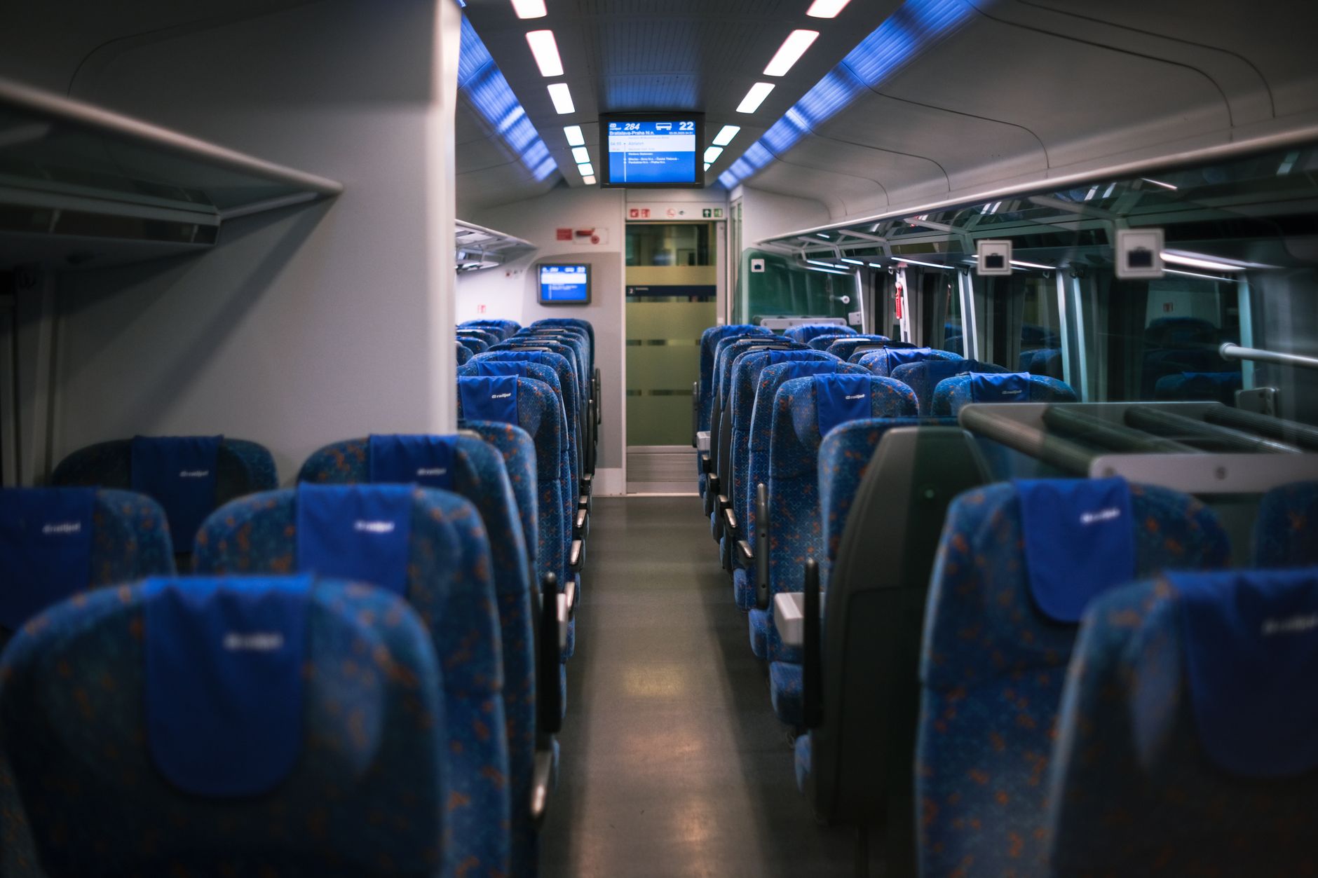 Mavi koltukları ve üst bagaj bölmeleriyle modern bir lüks tren vagonunun iç görünümü.