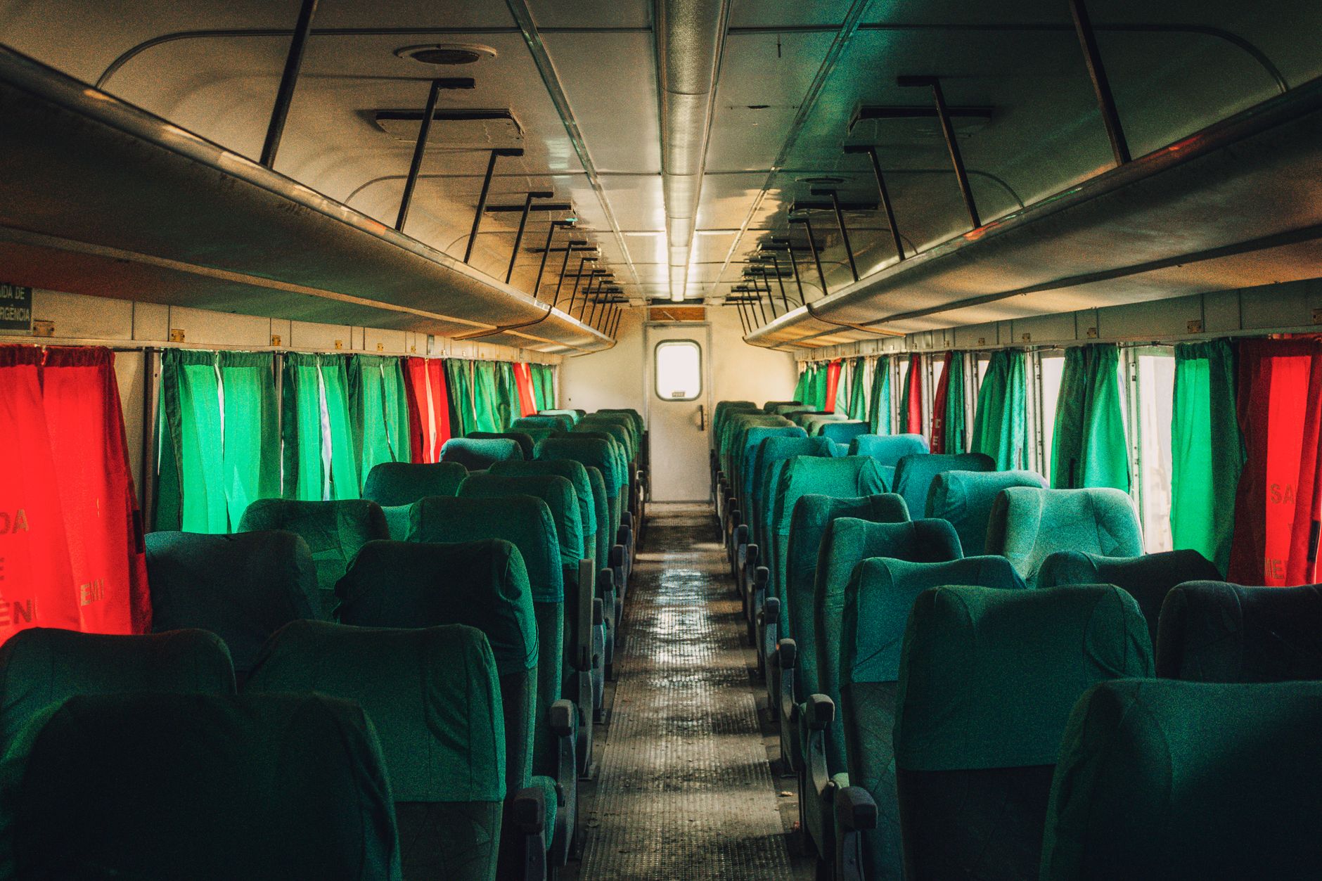 Interior view of a high-speed train featuring green seats and colorful curtains.