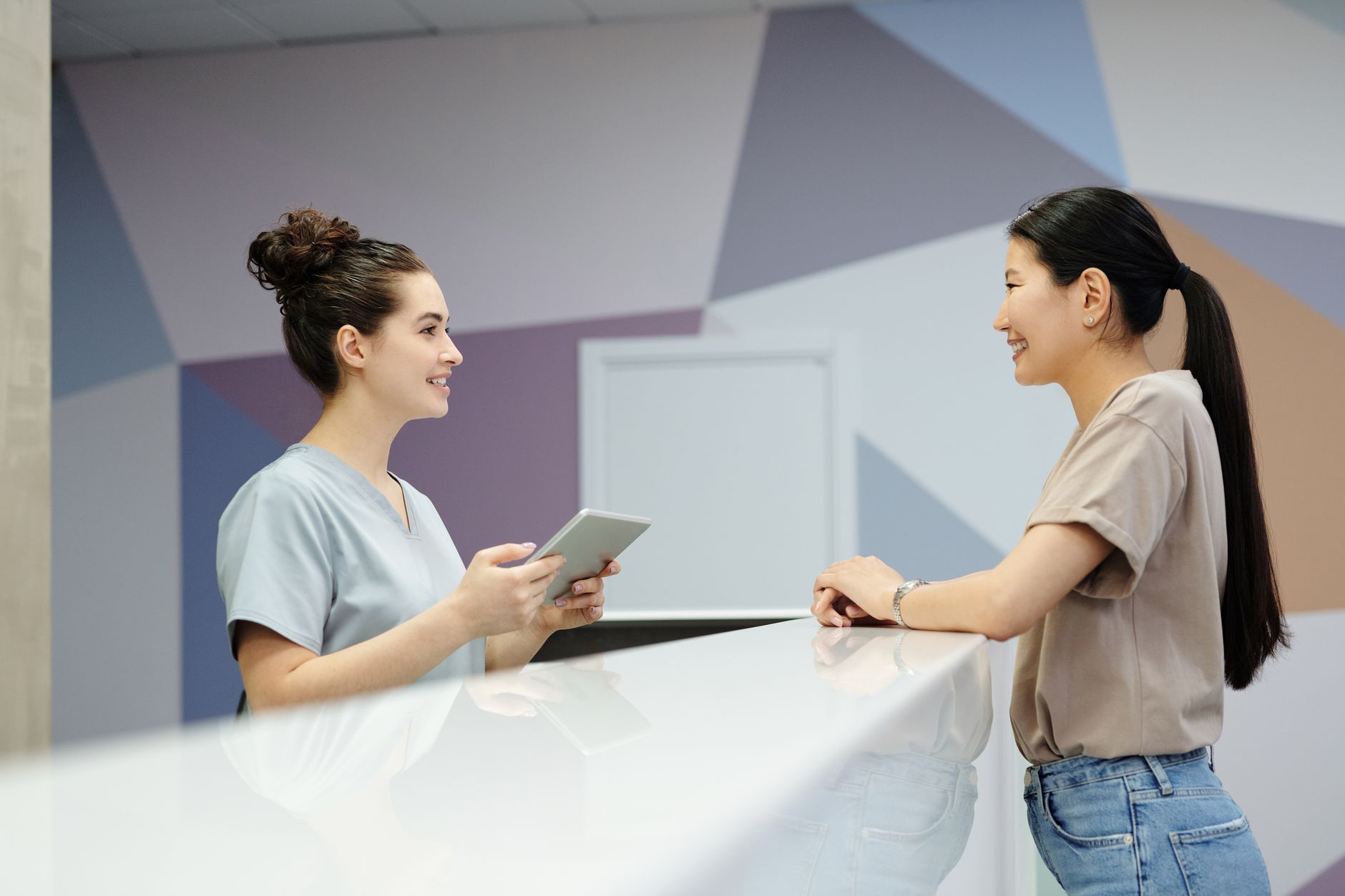 Healthcare professional assisting a patient at a help desk in a modern Turkish hospital.