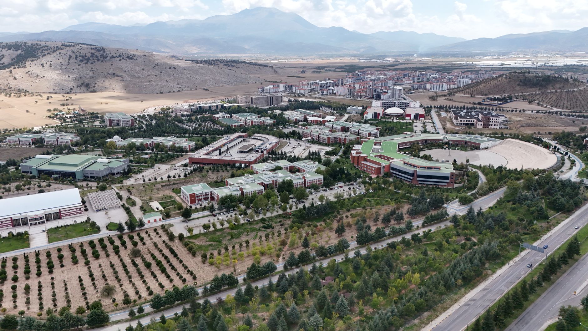Aerial image showcasing a university hospital complex surrounded by mountains and cityscapes.