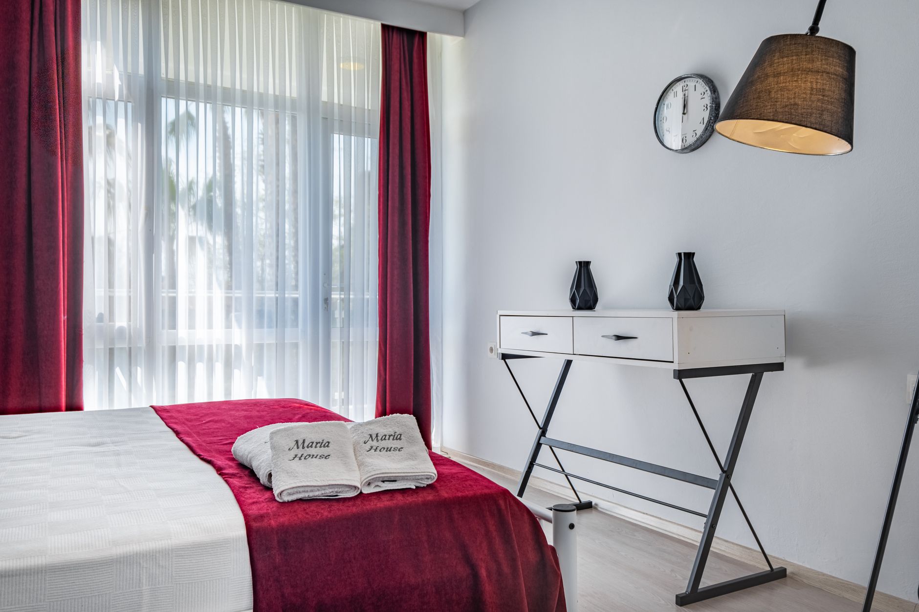 Serene hotel room in Antalya featuring red accents, towels, and modern decor.