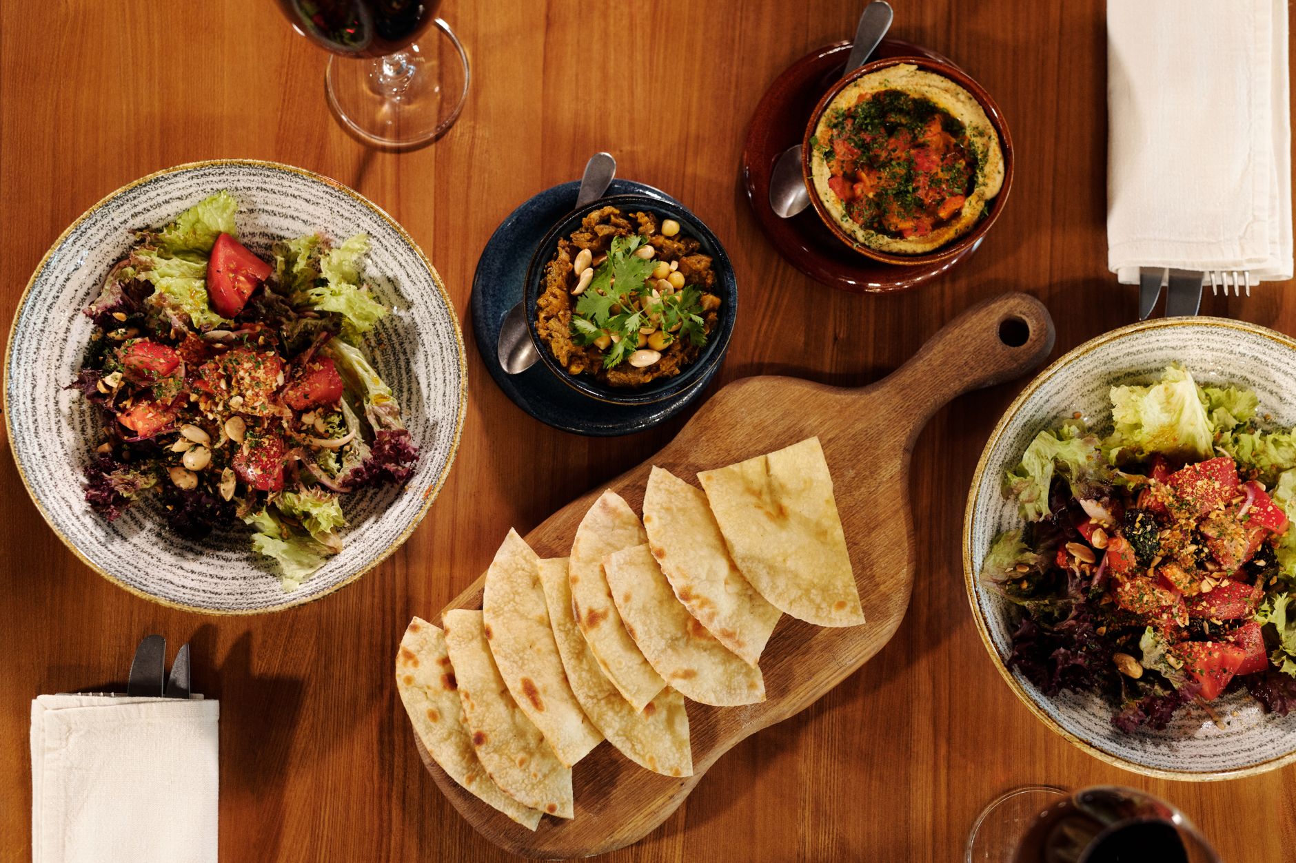 A vibrant spread of salads, mezes, and flatbreads on a wooden table.
