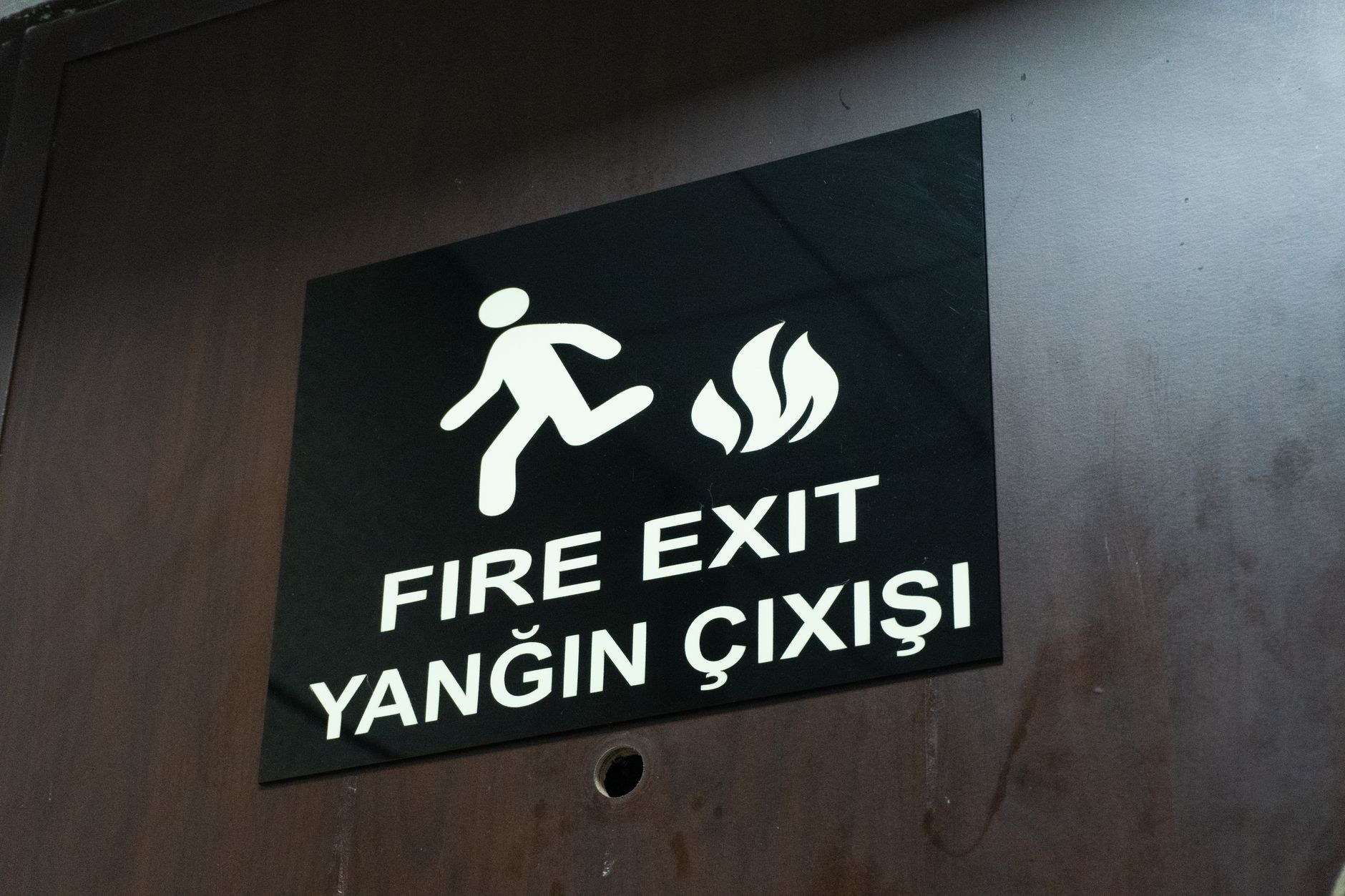 Bilingual fire exit sign indicating safe evacuation route at a Turkish hospital.