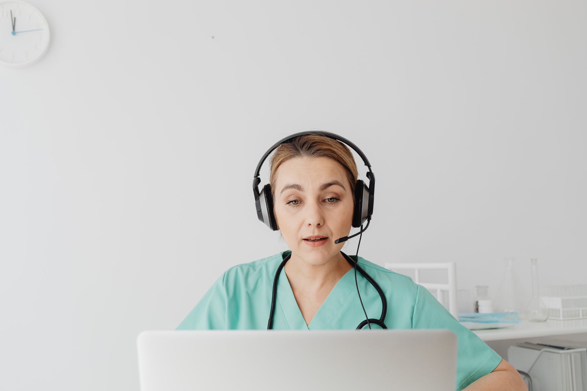 A healthcare professional in scrubs using a headset for video remote interpretation in a modern hospital setting.