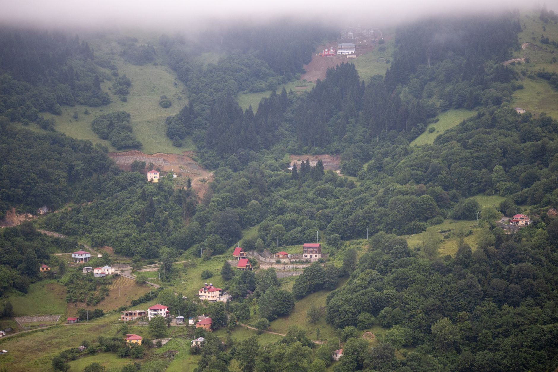 Aerial view of a traditional village near Bafra, featuring houses and tea gardens amidst lush green hills.