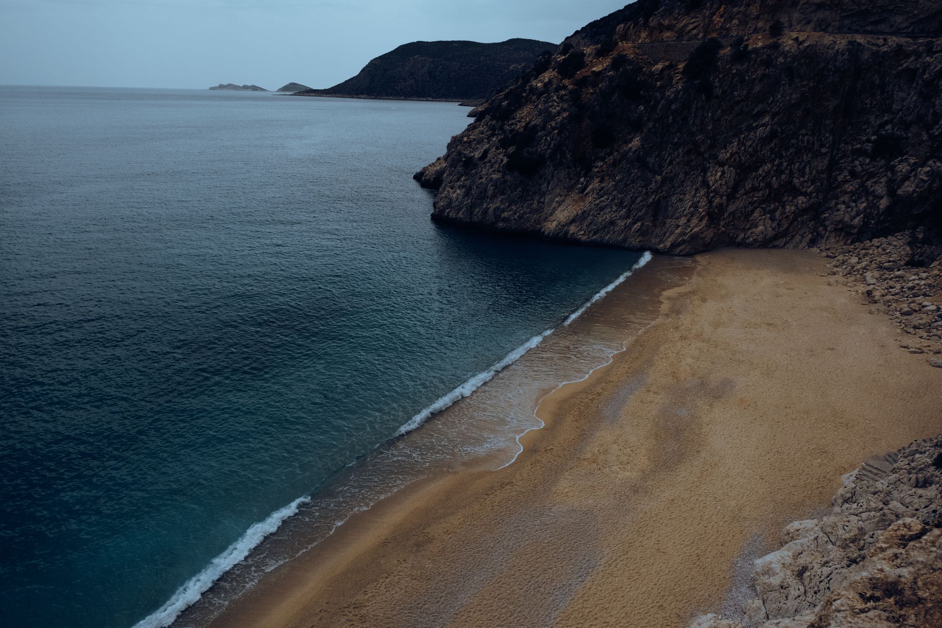 Wide empty sandy beach along the Black Sea, featuring dunes and driftwood.