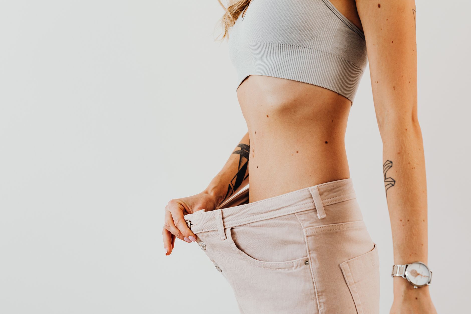 A person shows off loose-fitting pants, celebrating weight loss progress.