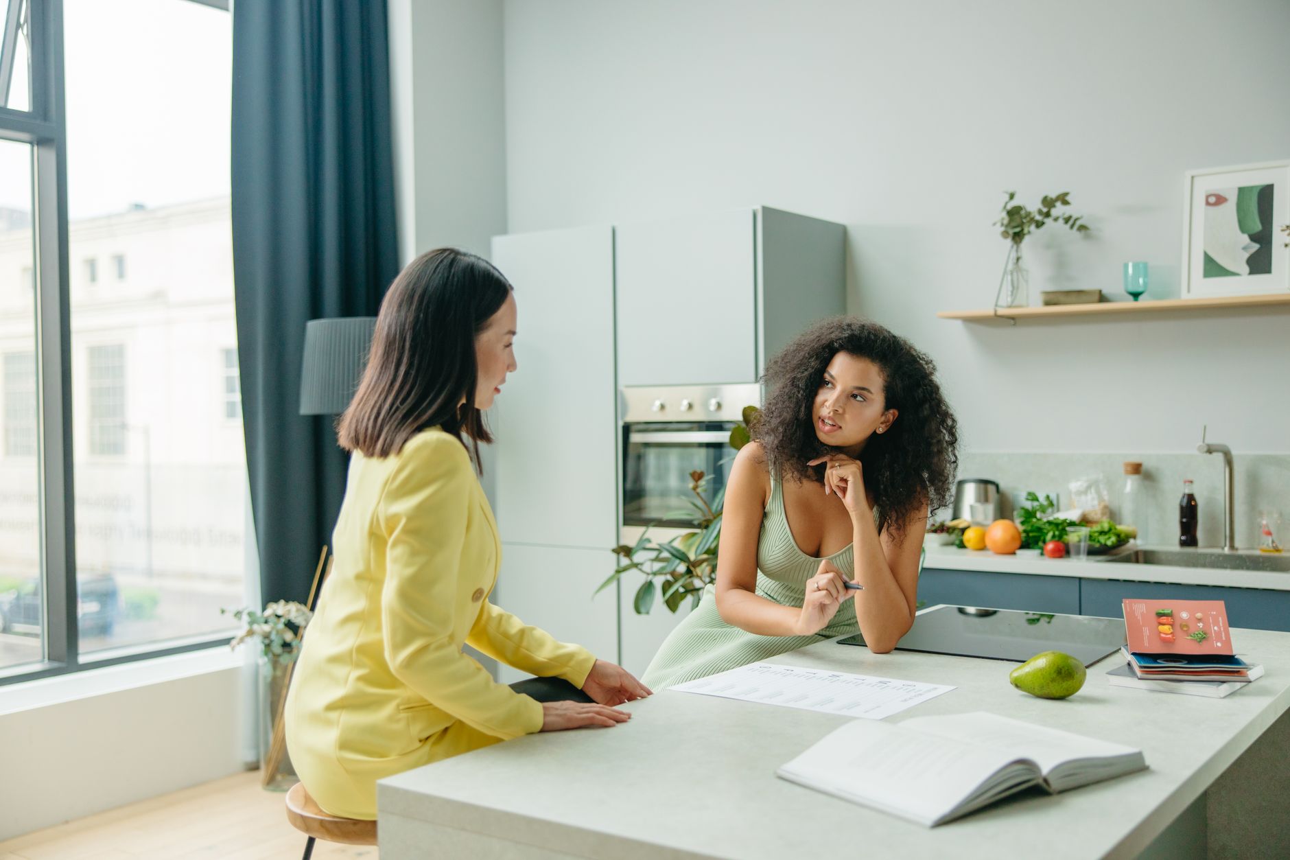 Two women discussing a post-operative diet plan in a stylish kitchen.