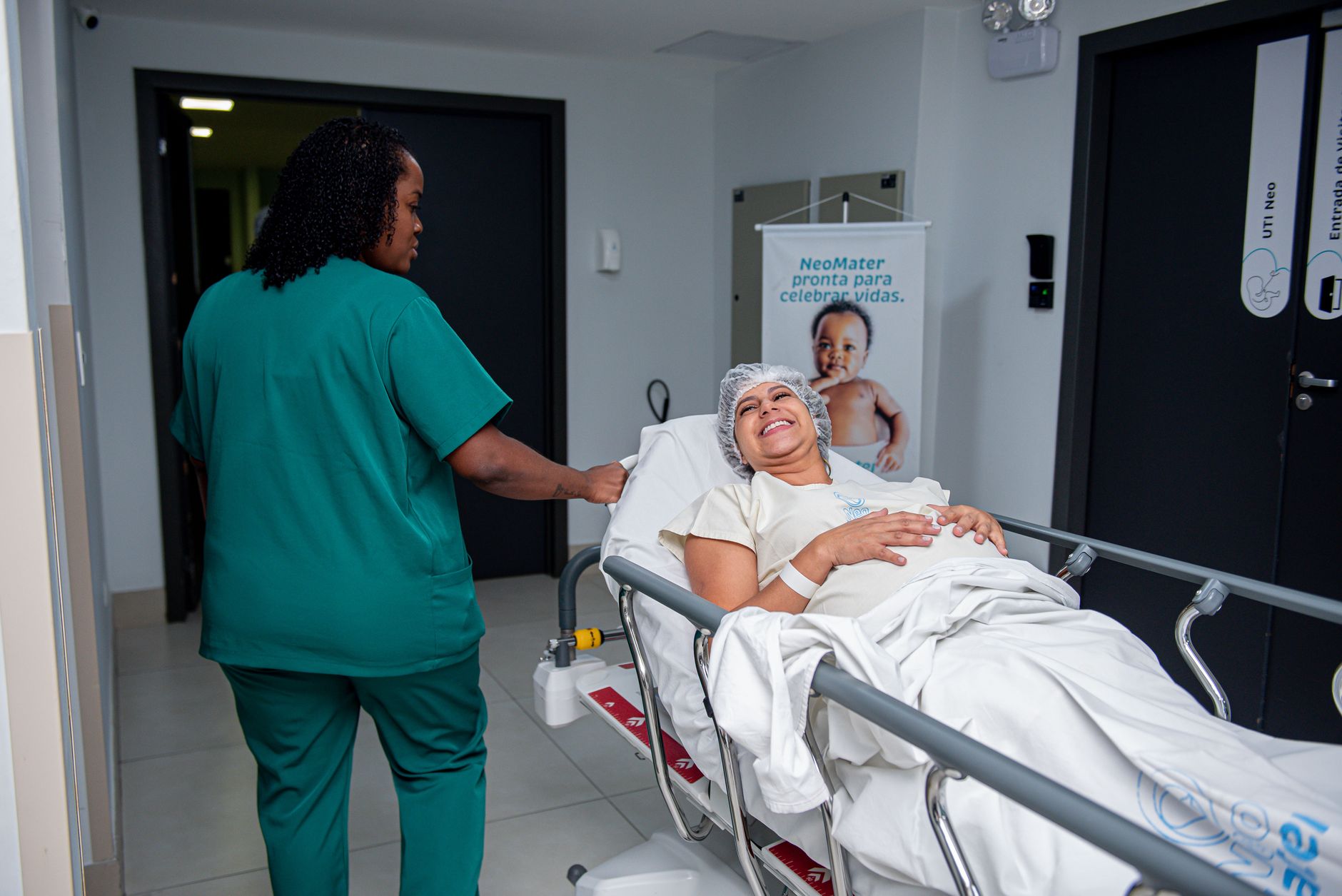 A happy patient in a hospital bed smiles as a nurse assists her.