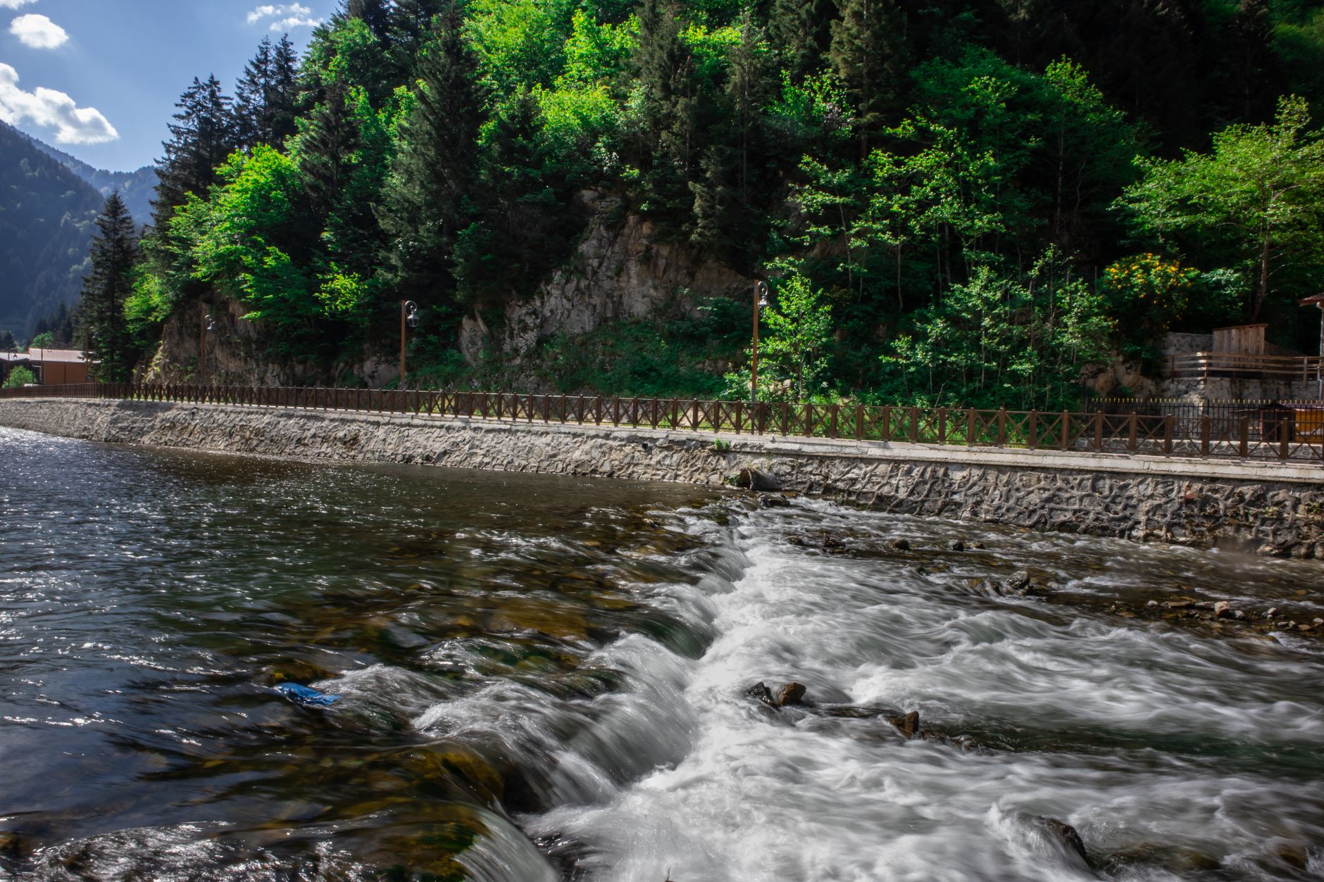 A scenic river view with lush greenery and walking path in Trabzon, ideal for recovery.