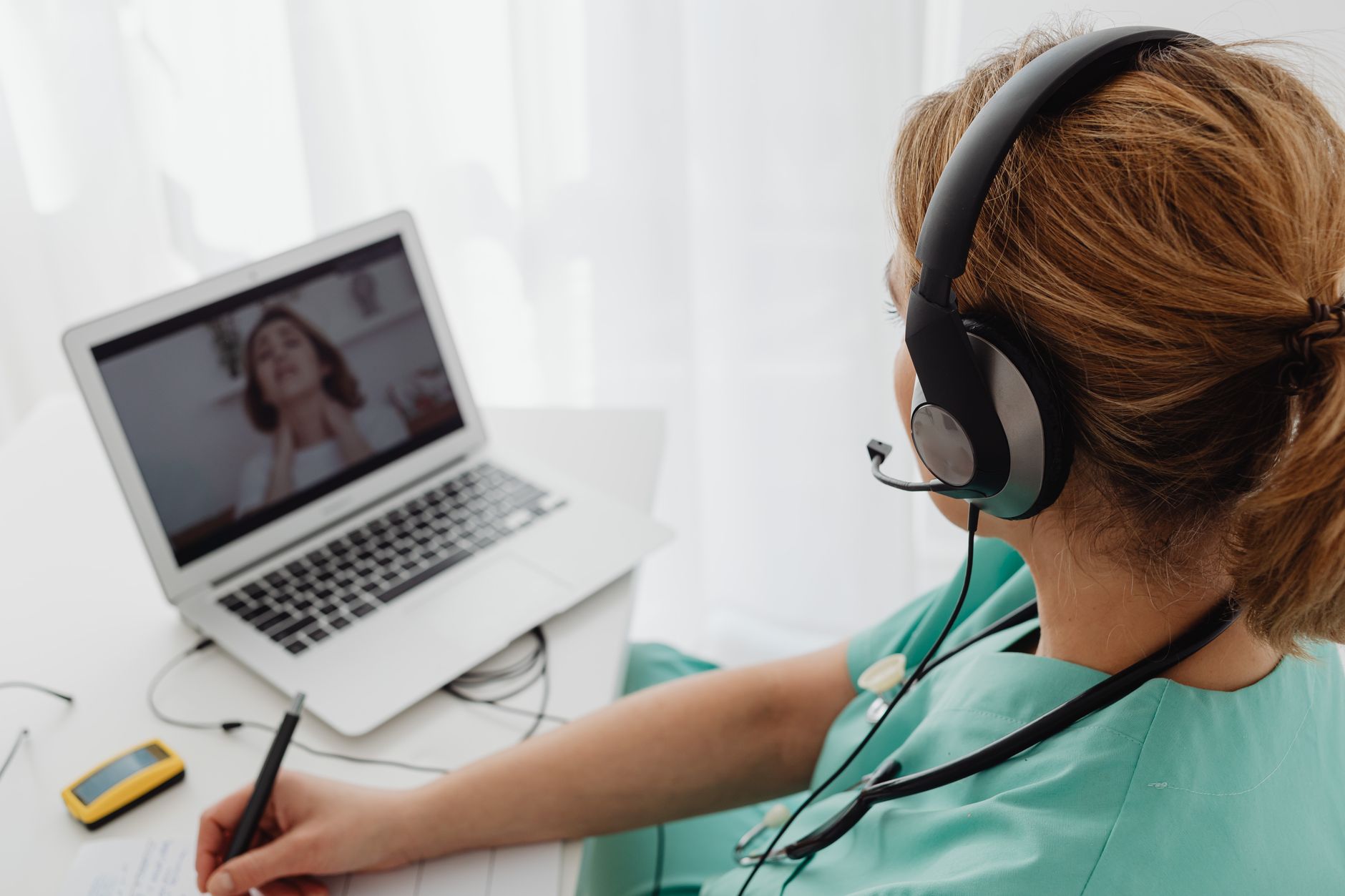 A dietitian in scrubs wearing a headset conducts a video consultation.