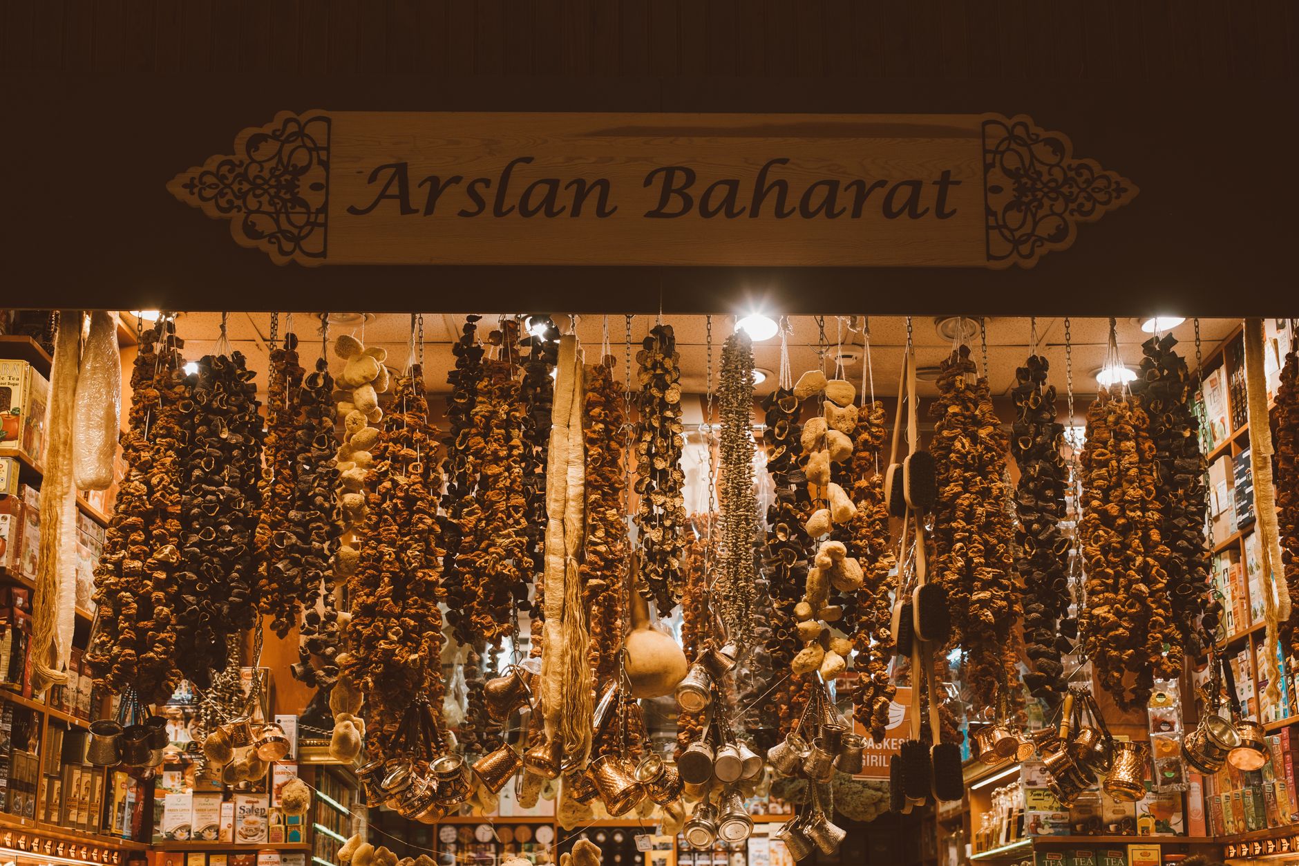 بهارات وإكسسوارات معلقة في متجر Arslan Baharat للبهارات في إسطنبول، تعرض مشهداً نابضاً بالحياة في السوق.