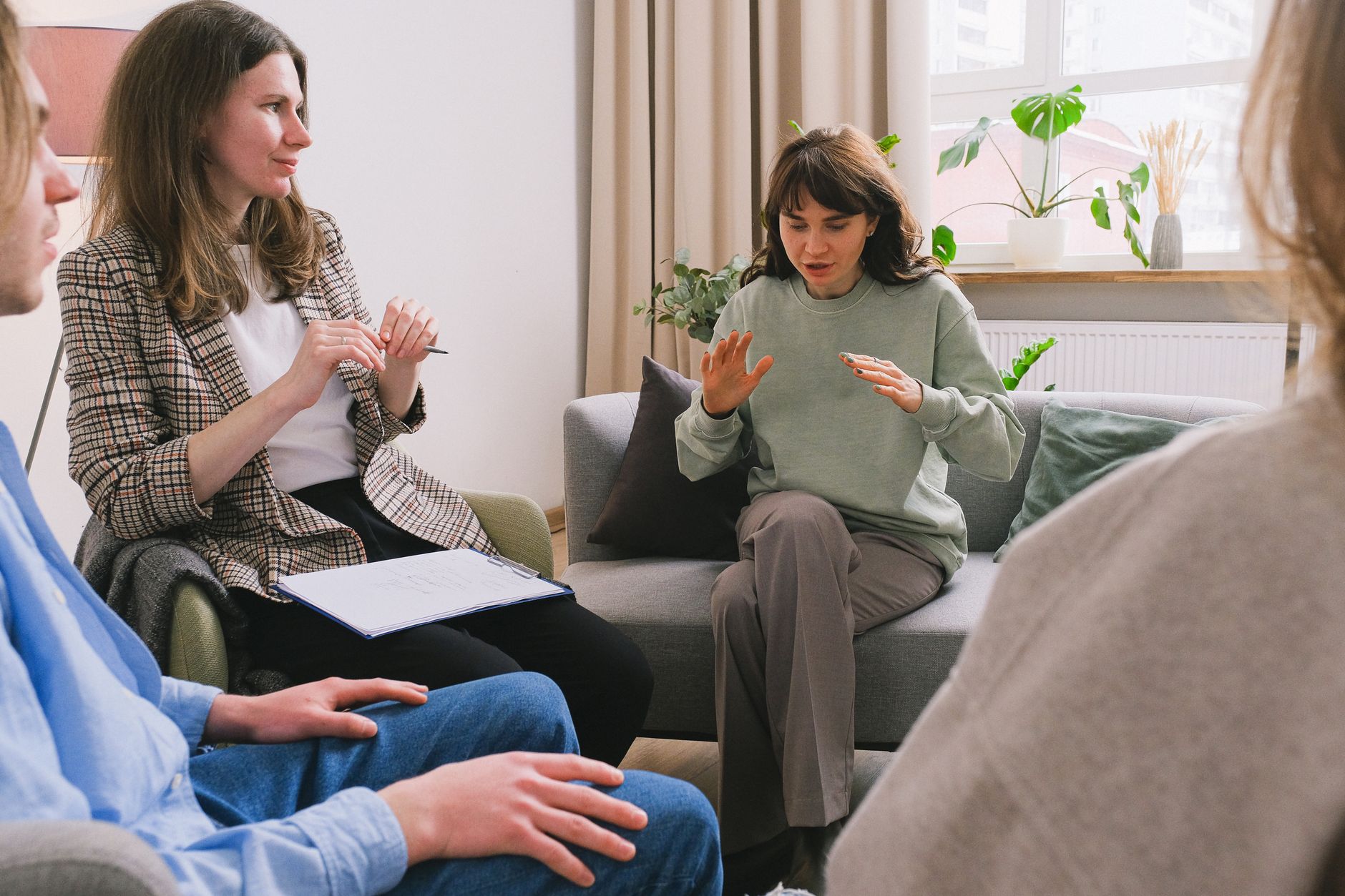 Group session with participants discussing in a bright room, focusing on support and communication.