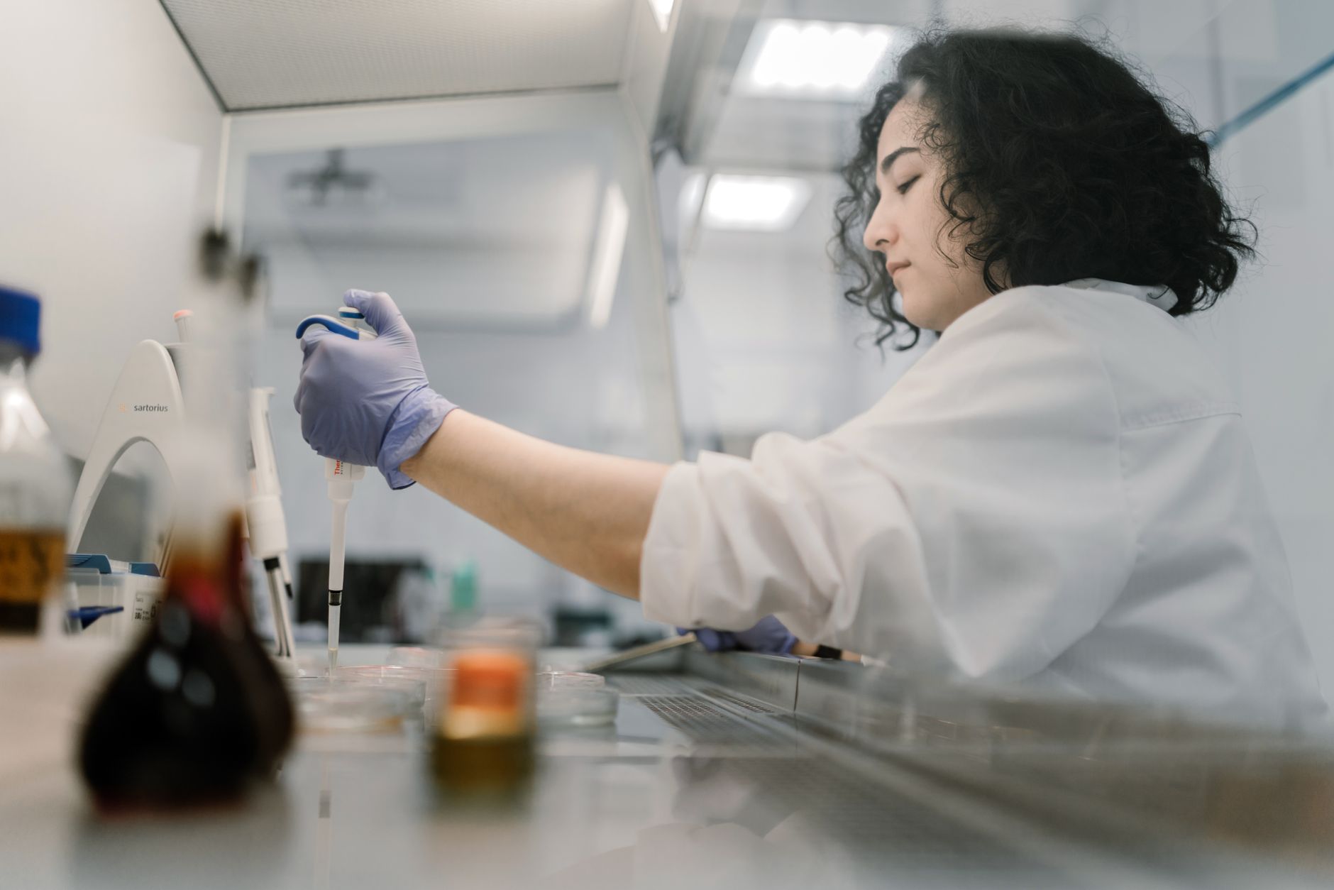 A scientist in a lab coat using a pipette in a stem cell processing lab.