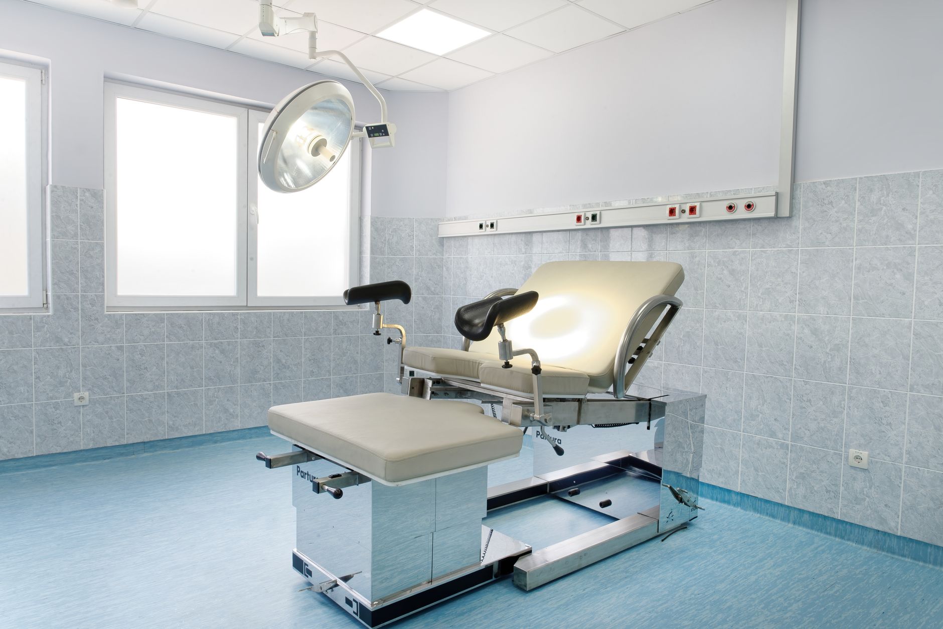 A clean examination room with a medical chair and bright lighting, designed for infection control.