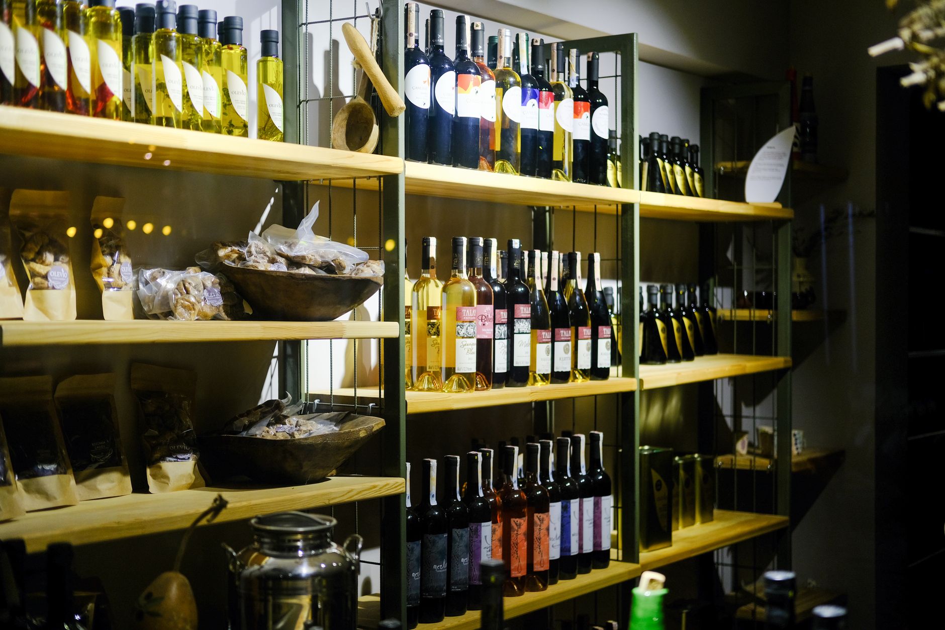 Shelves filled with wine bottles and olive oils, showcasing a variety of products.