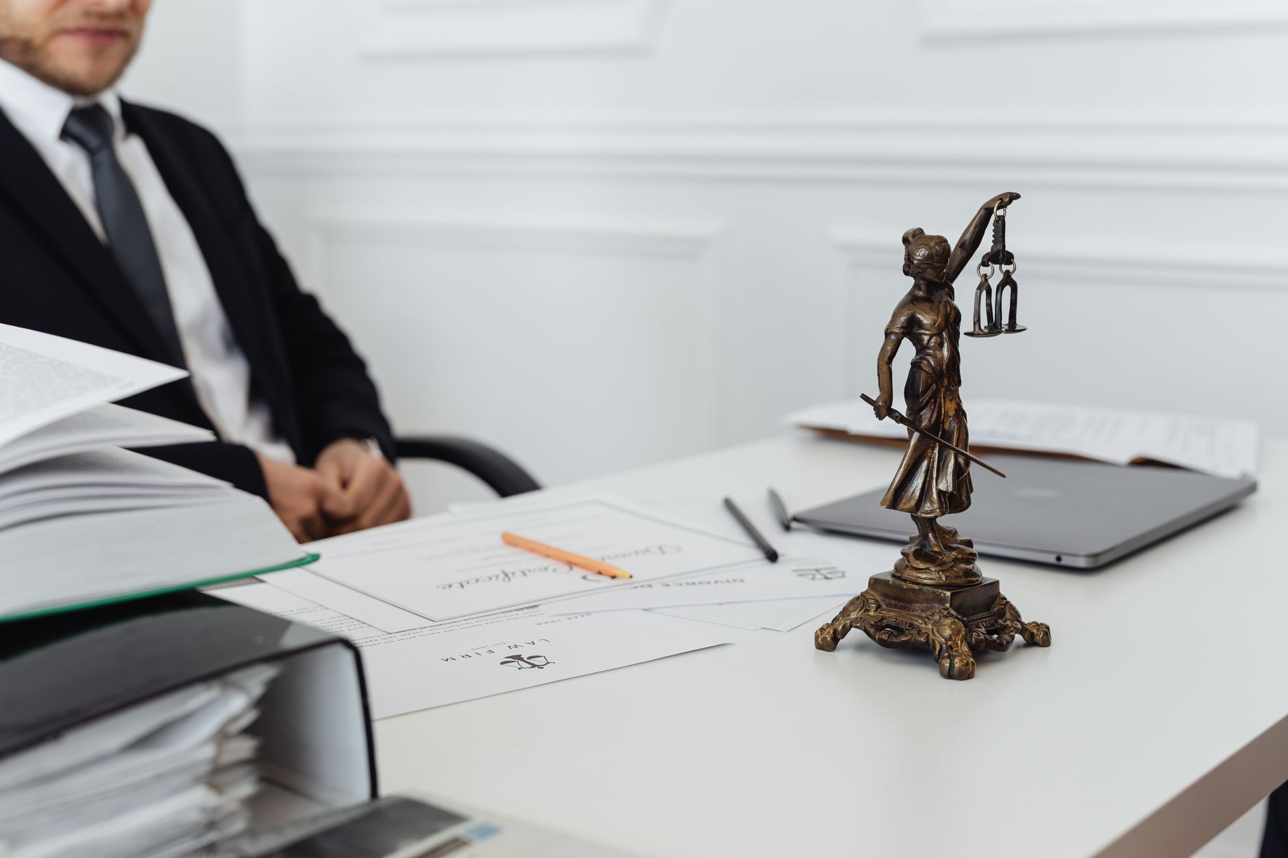 Lawyer's desk featuring a Lady Justice statue and medical documents ready for notarisation.