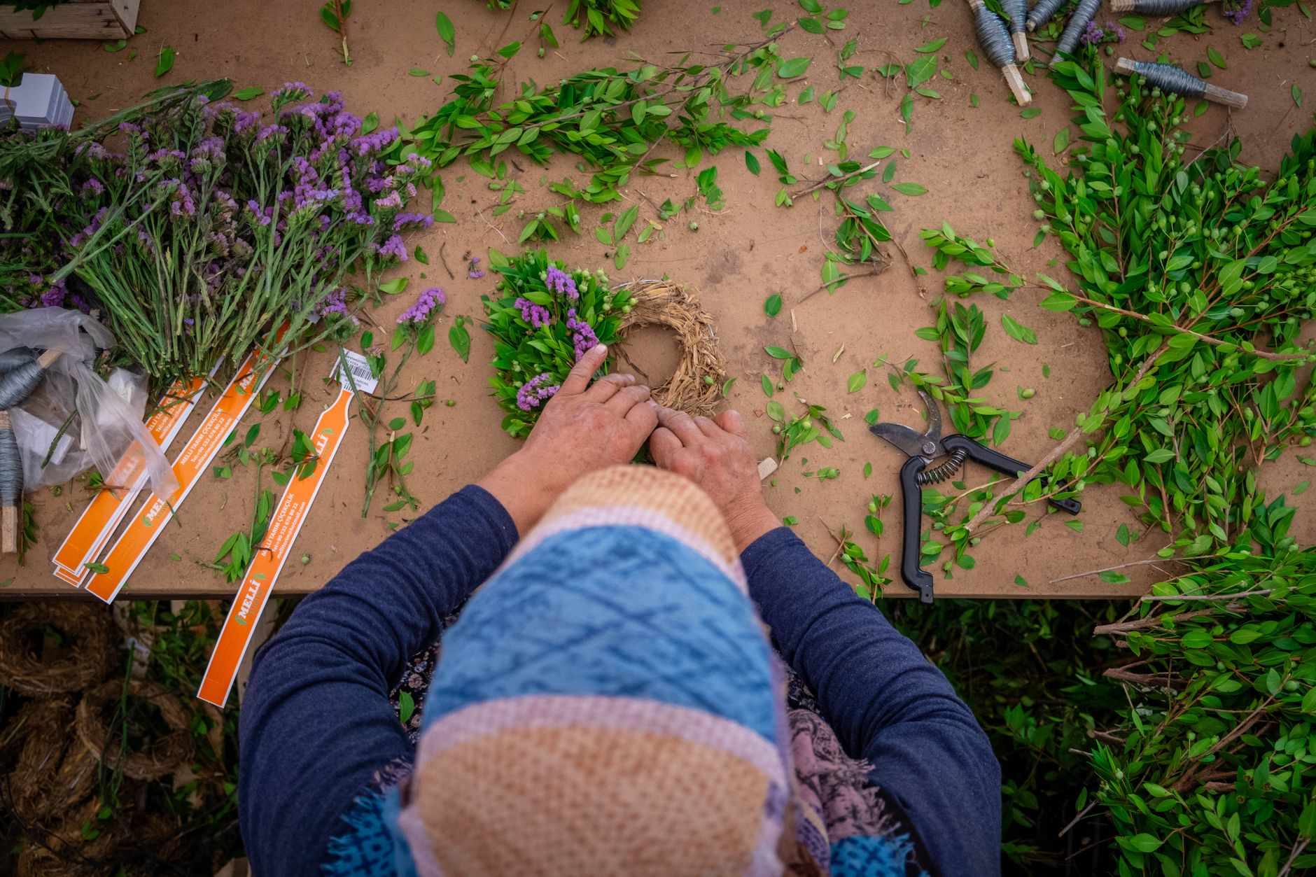 A person assembling a floral wreath with lavender and greens at the Lavender Festival.
