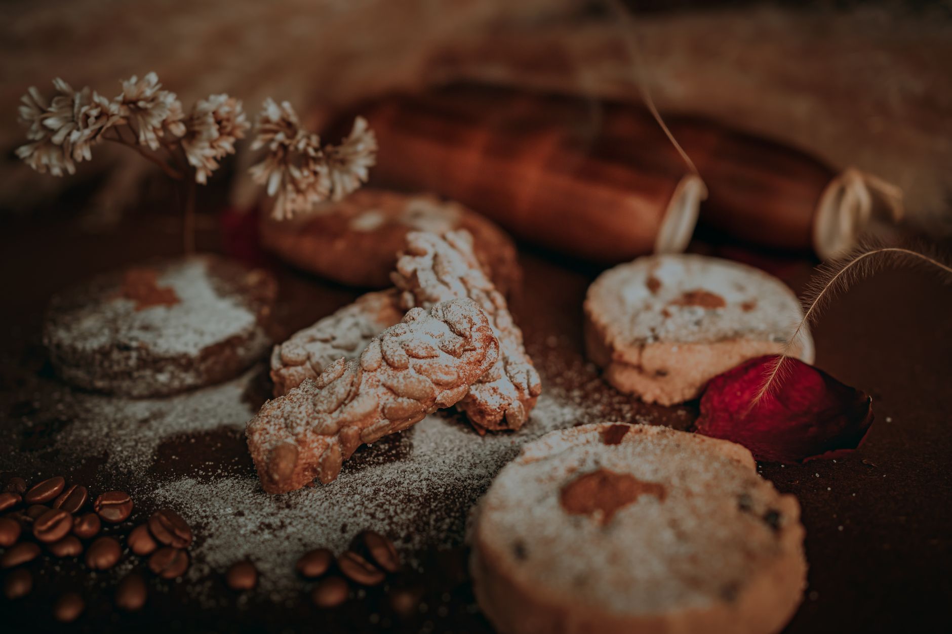 Close-up of various cookies dusted with powdered sugar, with flowers and coffee beans.