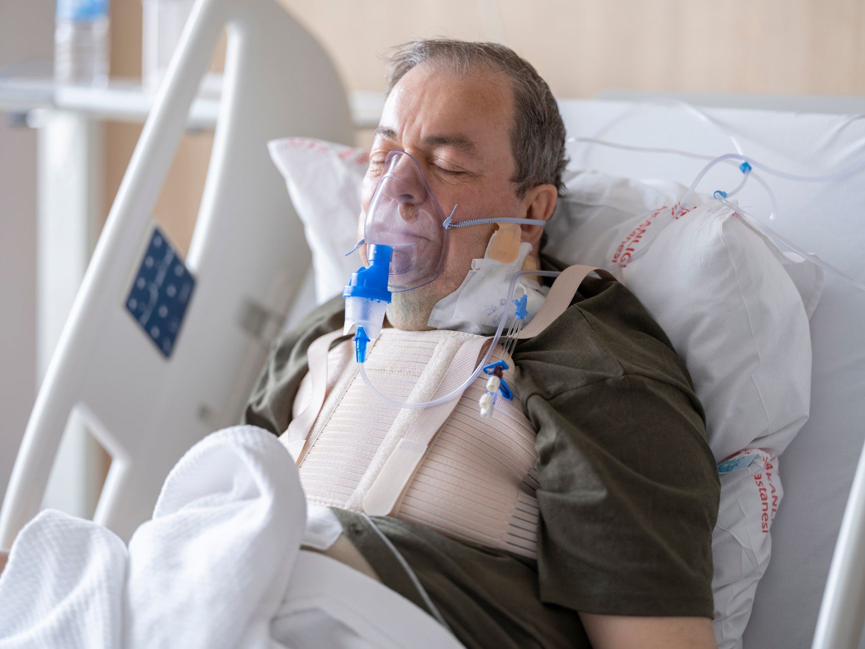 Patient resting in hospital bed, receiving oxygen therapy during cardiac rehabilitation.