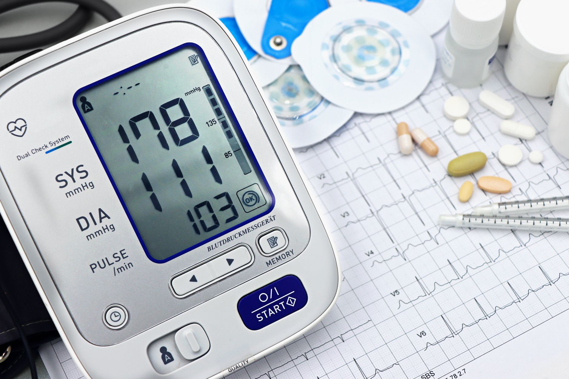 Blood pressure monitor showing 178/111, with medications and ECG sheet in a cardiologist's office.