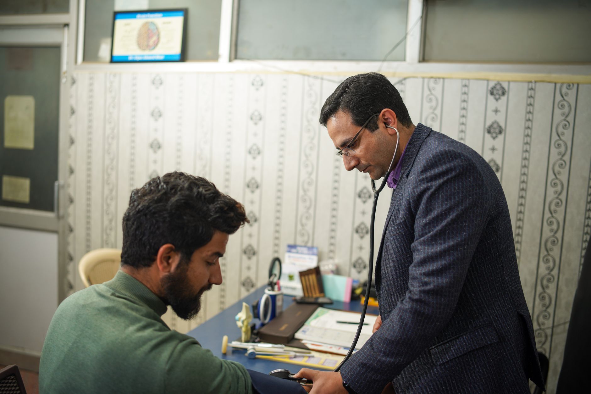A cardiologist checking a patient's blood pressure in a clinic.