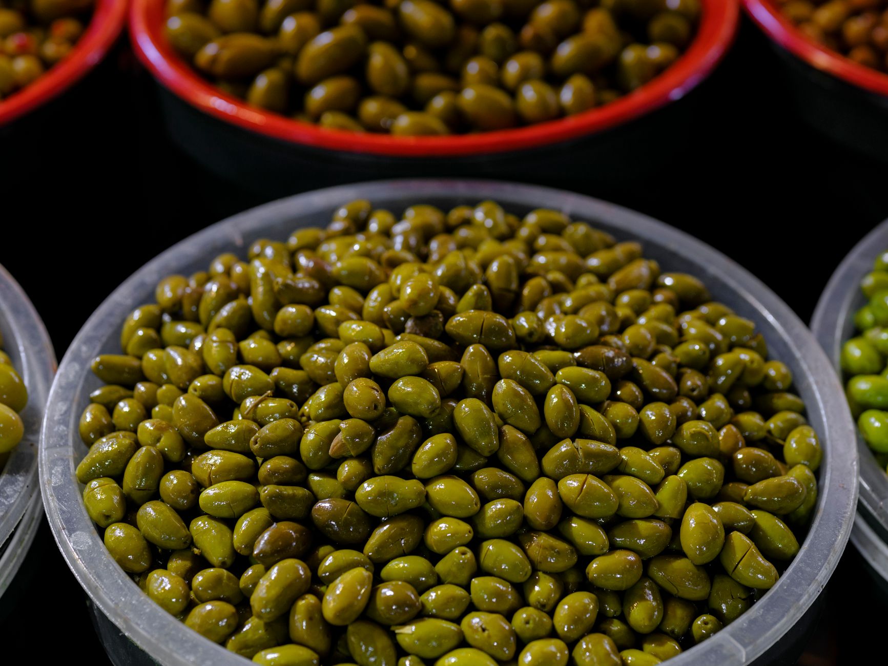 Close-up of green olives in bowls, showcasing vibrant colors, part of a Mediterranean diet.