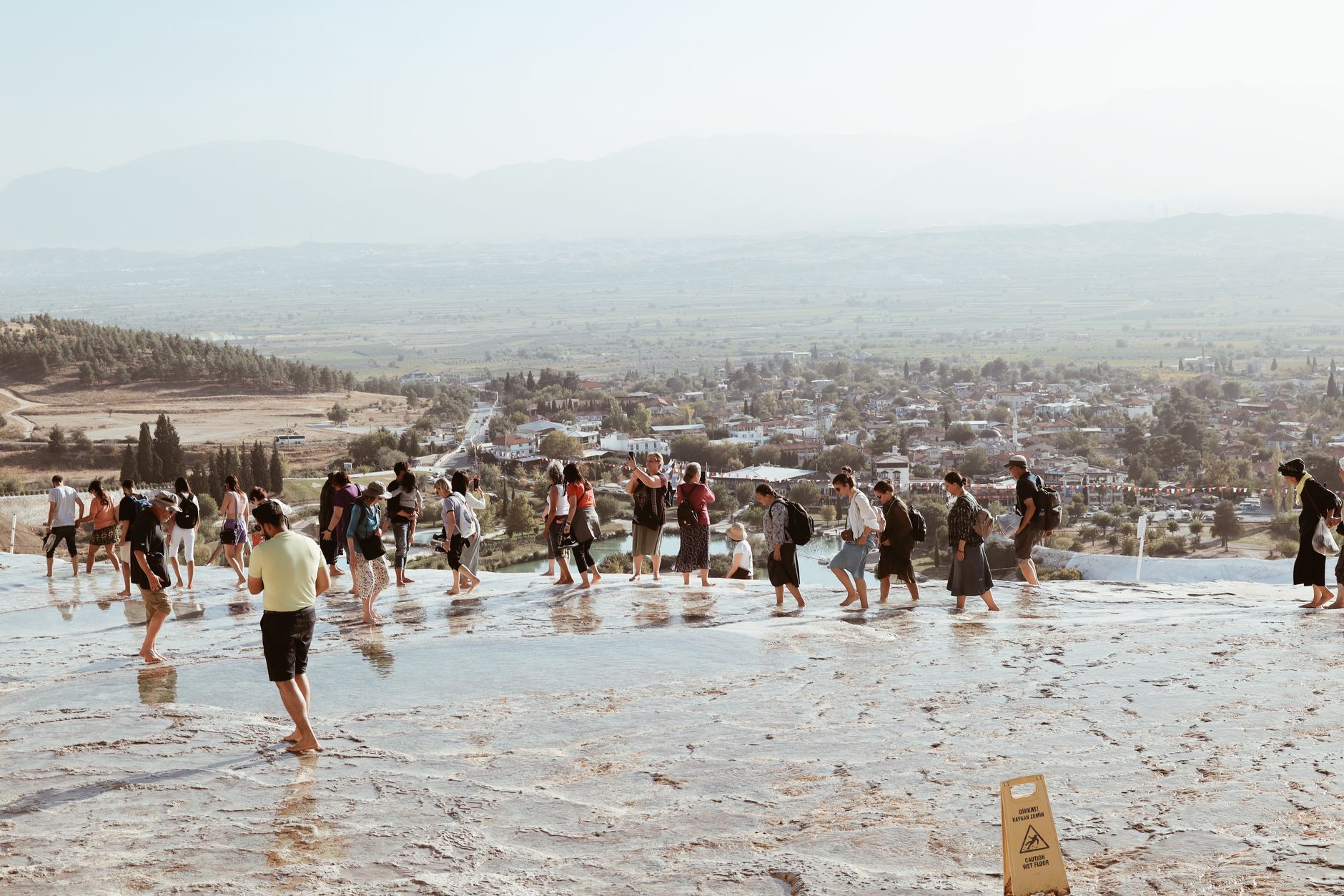 People walking through the thermal waters of Pamukkale, surrounded by scenic views.