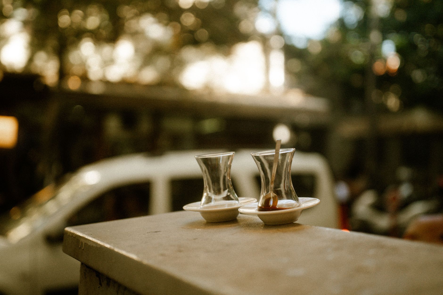 Two glasses of çay on white saucers at a village tea house, evoking social warmth.