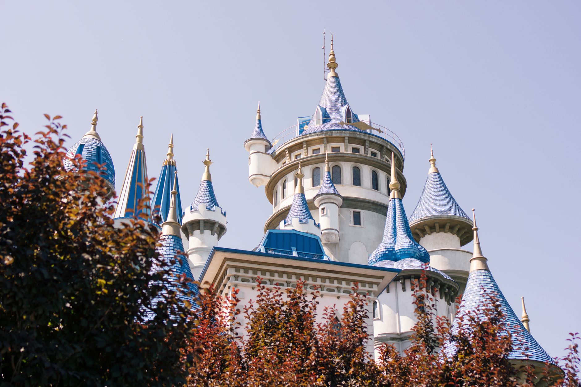 View of a fairy-tale castle with blue spires surrounded by greenery in Sazova Park.