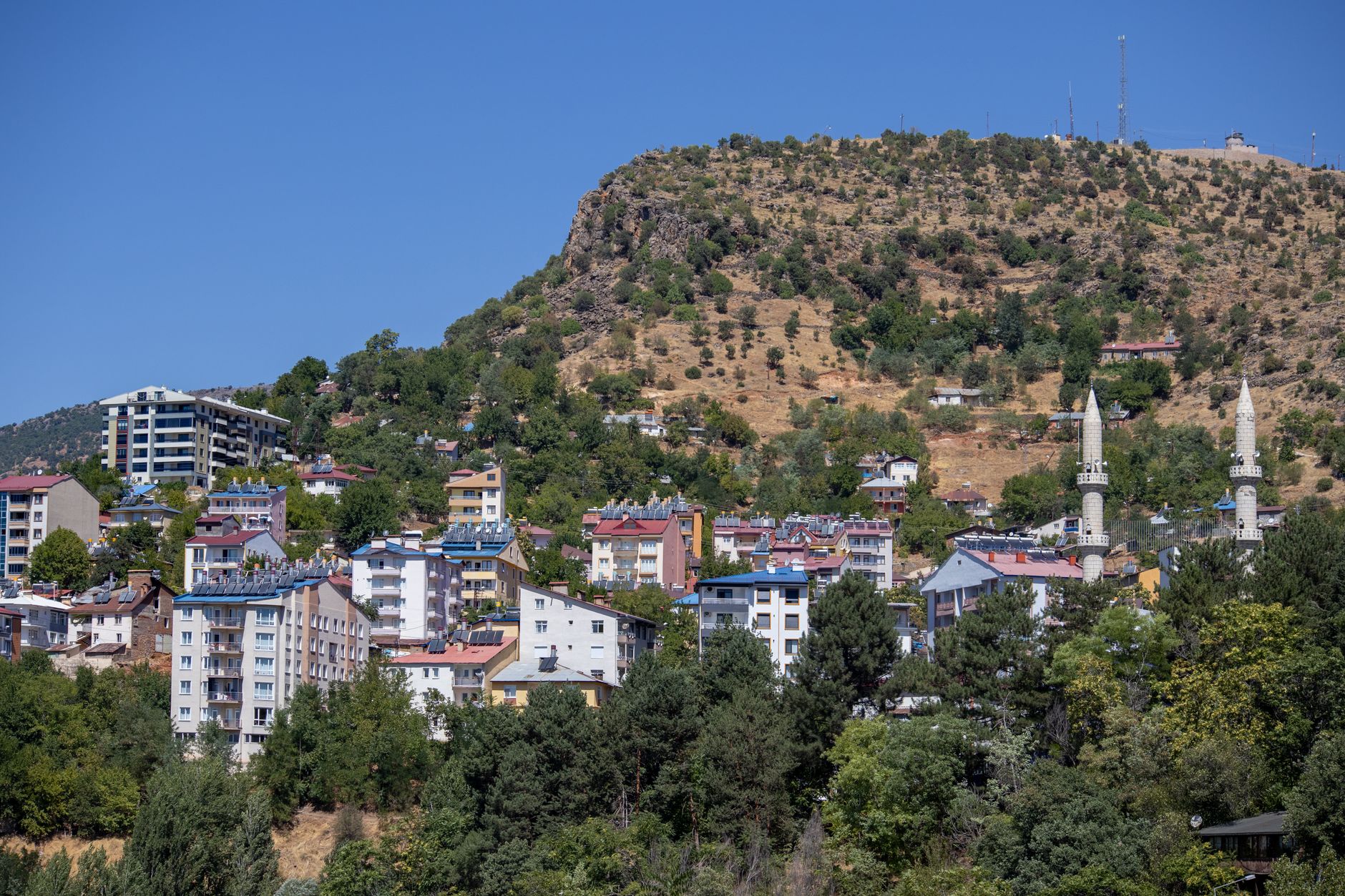 Dağlık bir manzaraya yaslanmış, çeşitli çatılara sahip küçük bir kasabanın pitoresk görünümü.