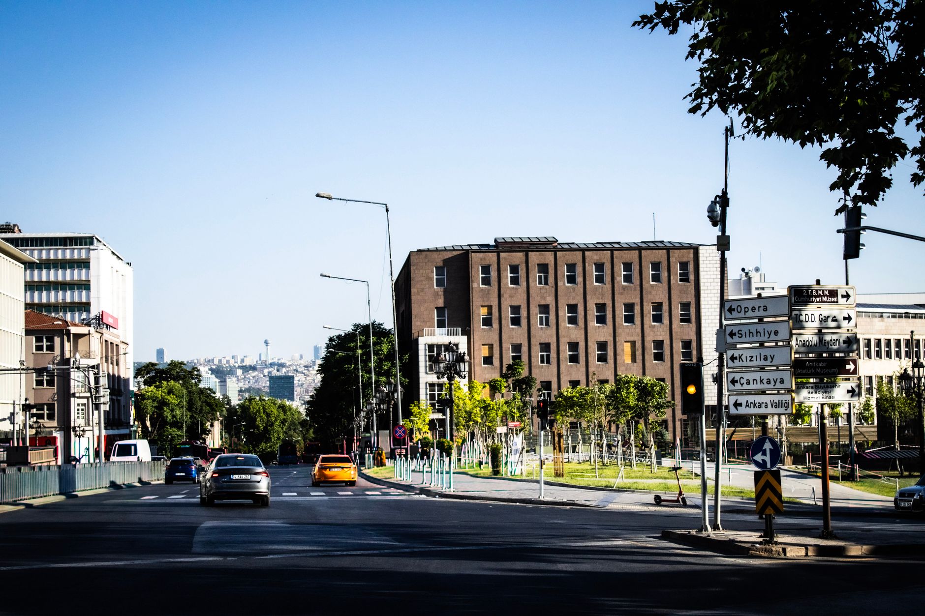 A busy street in Ankara featuring a modern building and traffic signs, symbolizing an academic medicine environment.