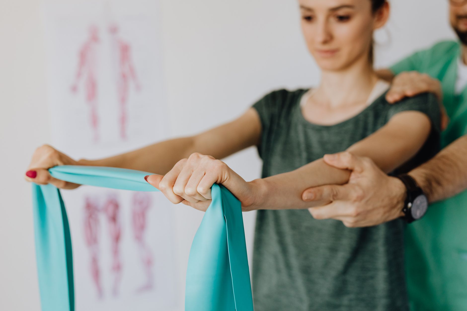 A physiotherapist guides a patient using a resistance band in a therapy session.