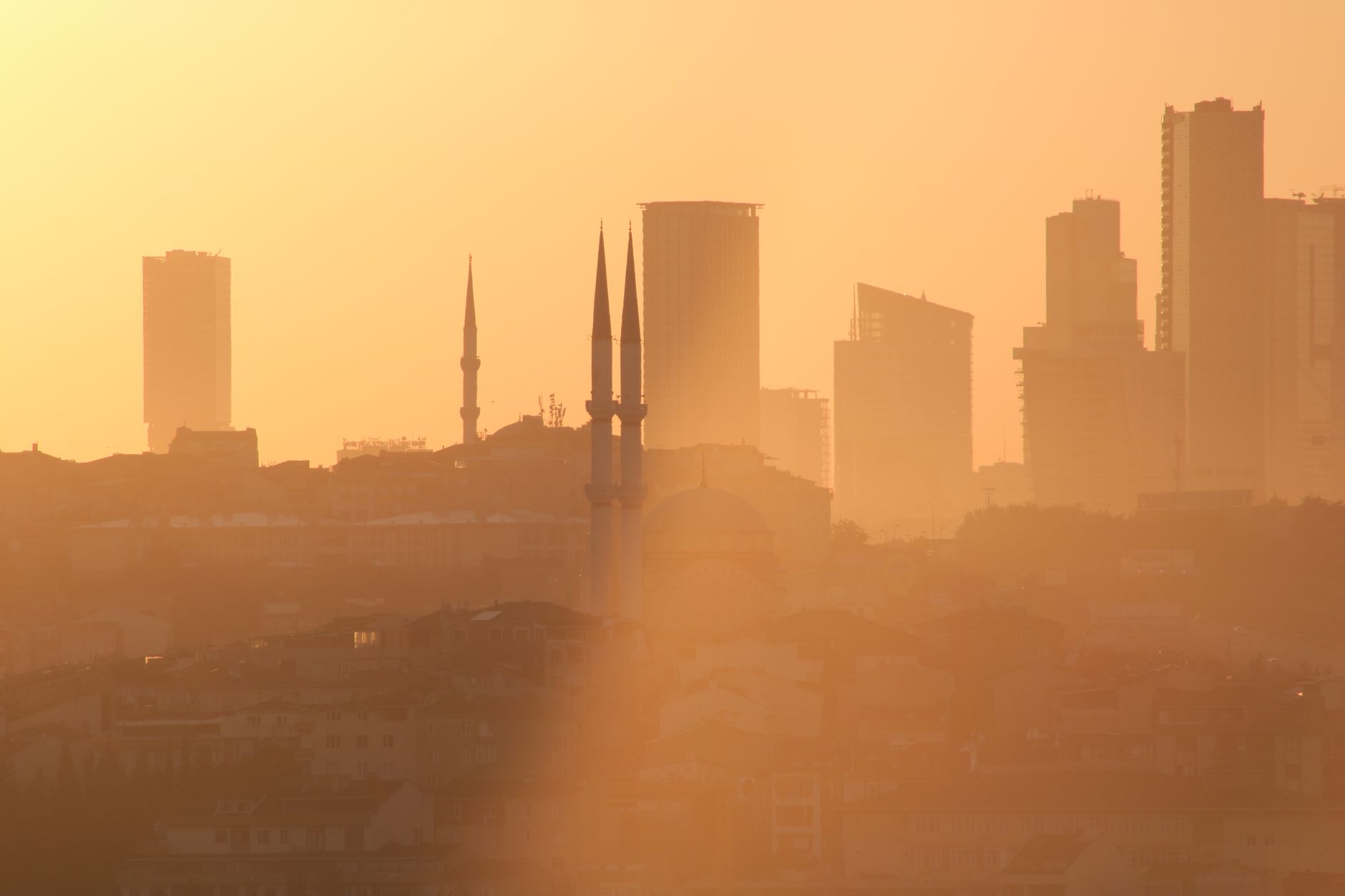 Silhouette of Istanbul's skyline at sunset, featuring minarets and skyscrapers.