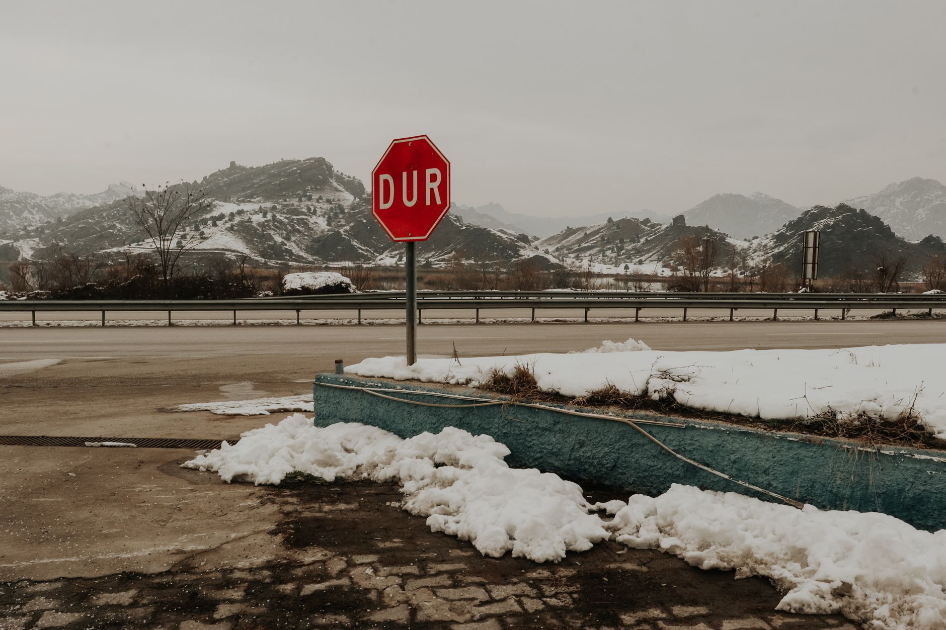 土耳其雪山公路旁一个写着“DUR”的停车标志，周围景色宁静。