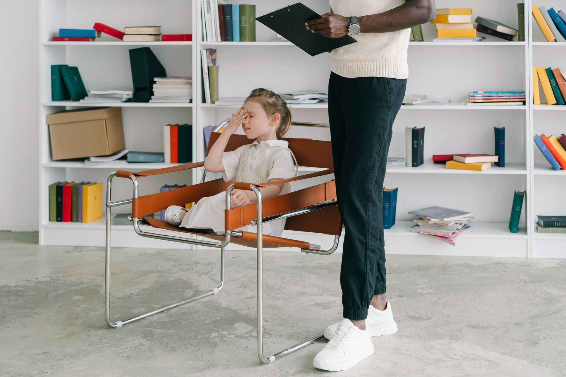 A child sitting in a chair looks frustrated during a speech therapy session.