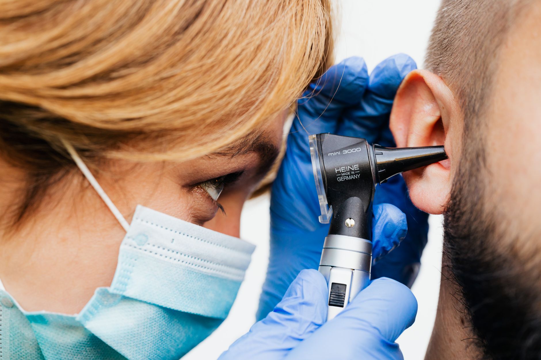 A healthcare professional examines a patient's ear with an otoscope.