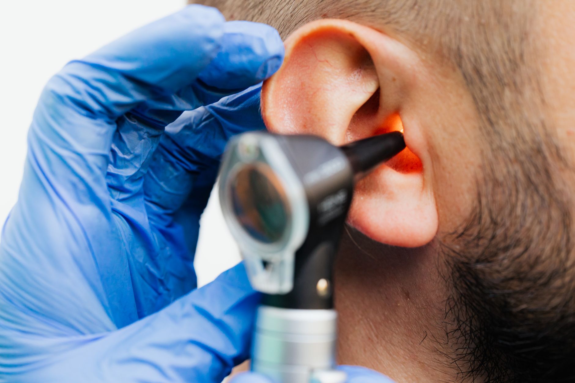 An audiologist inspects a child's ear using an otoscope in a clinical setting.