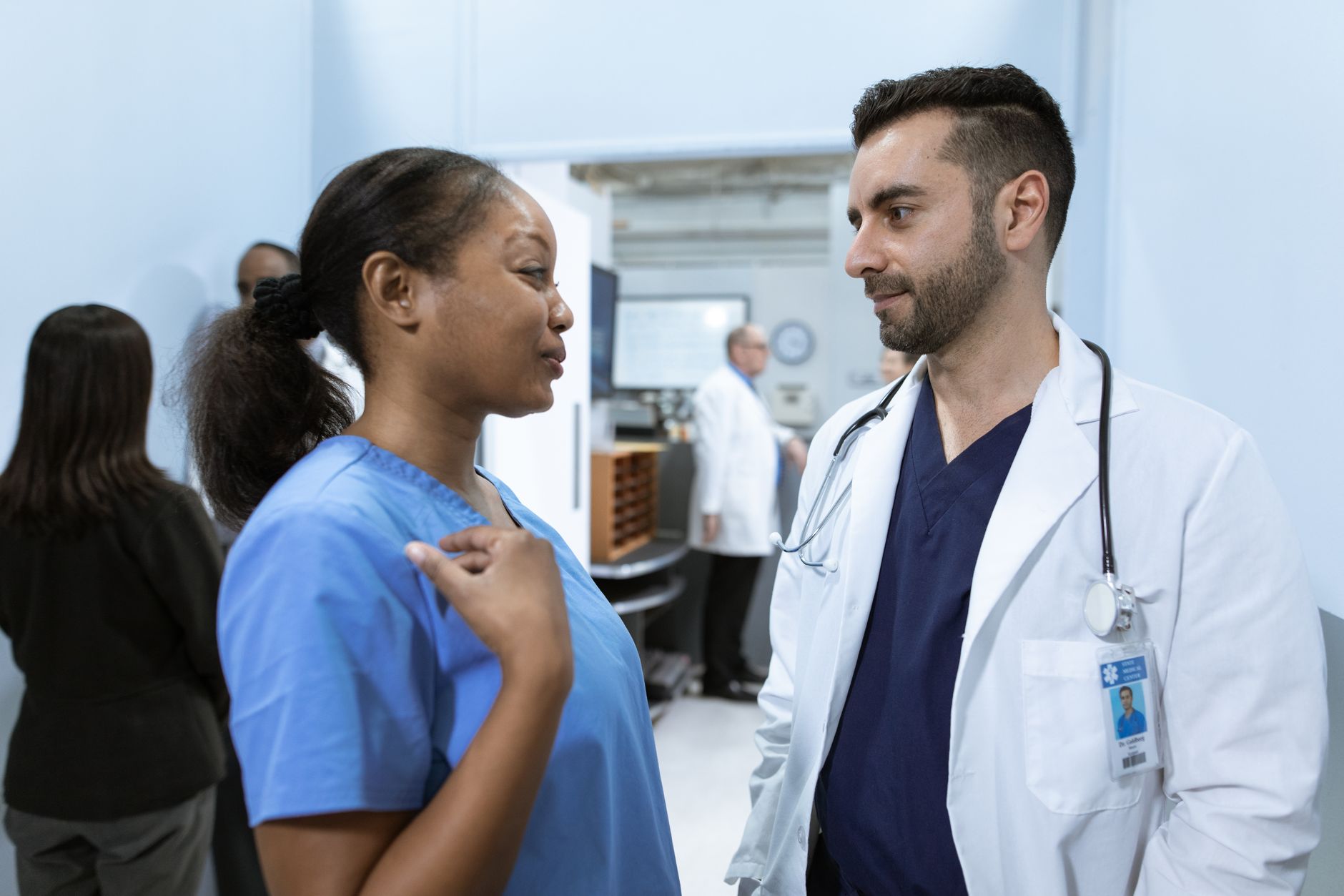 Female and male medical professionals discussing plans in a hospital corridor.