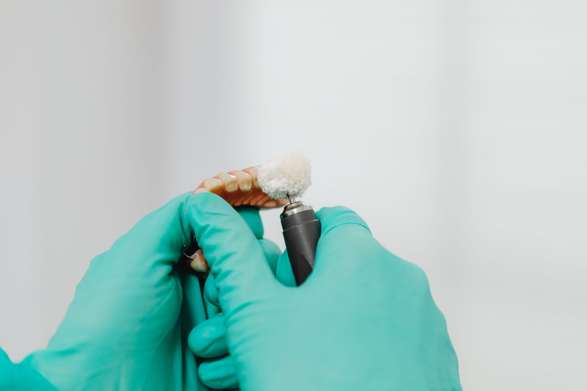 Dental professional polishing a zirconium crown with a rotary tool.