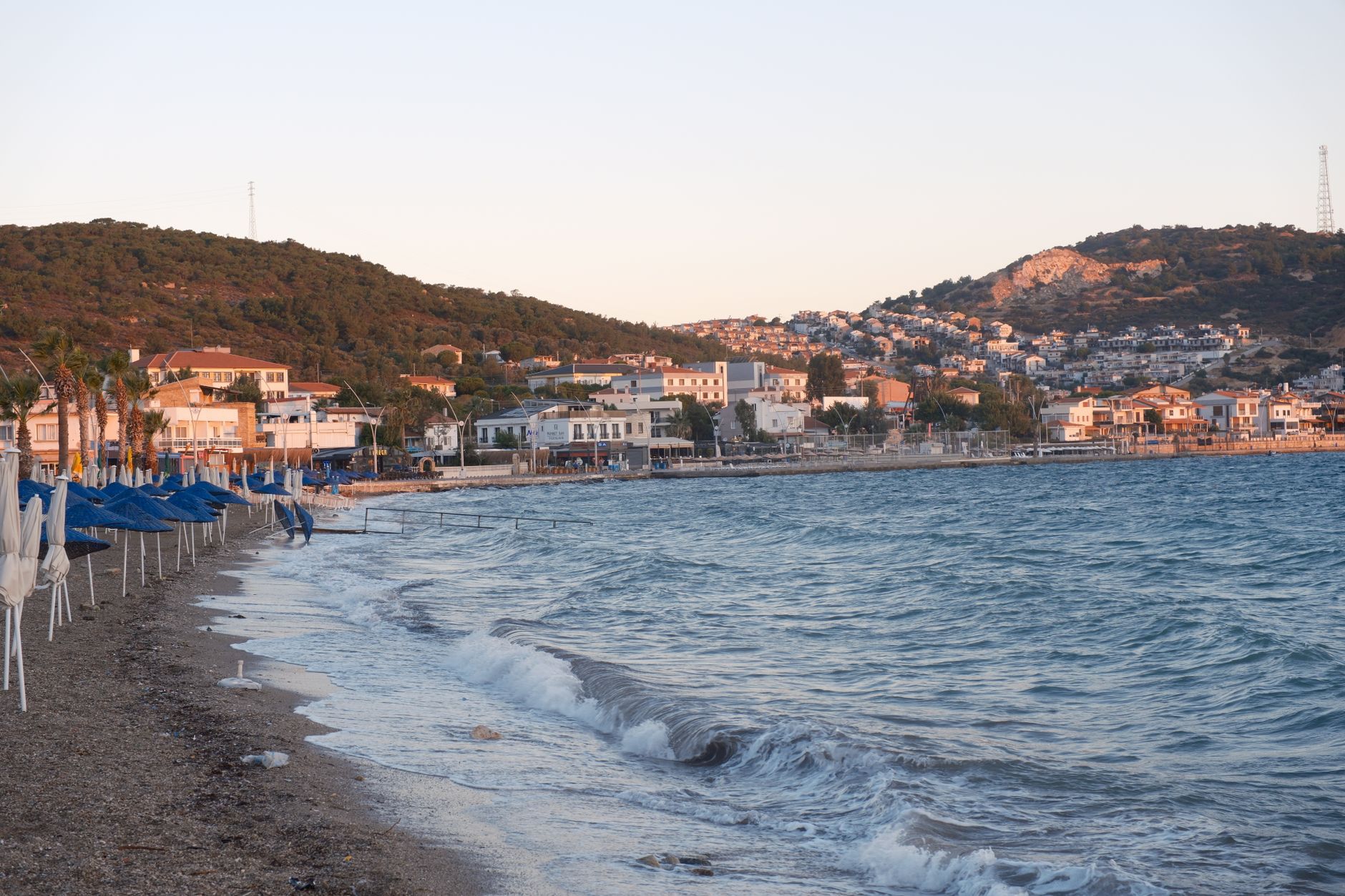 Alaçatı beach with clear waters and umbrellas, showcasing a peaceful holiday setting.